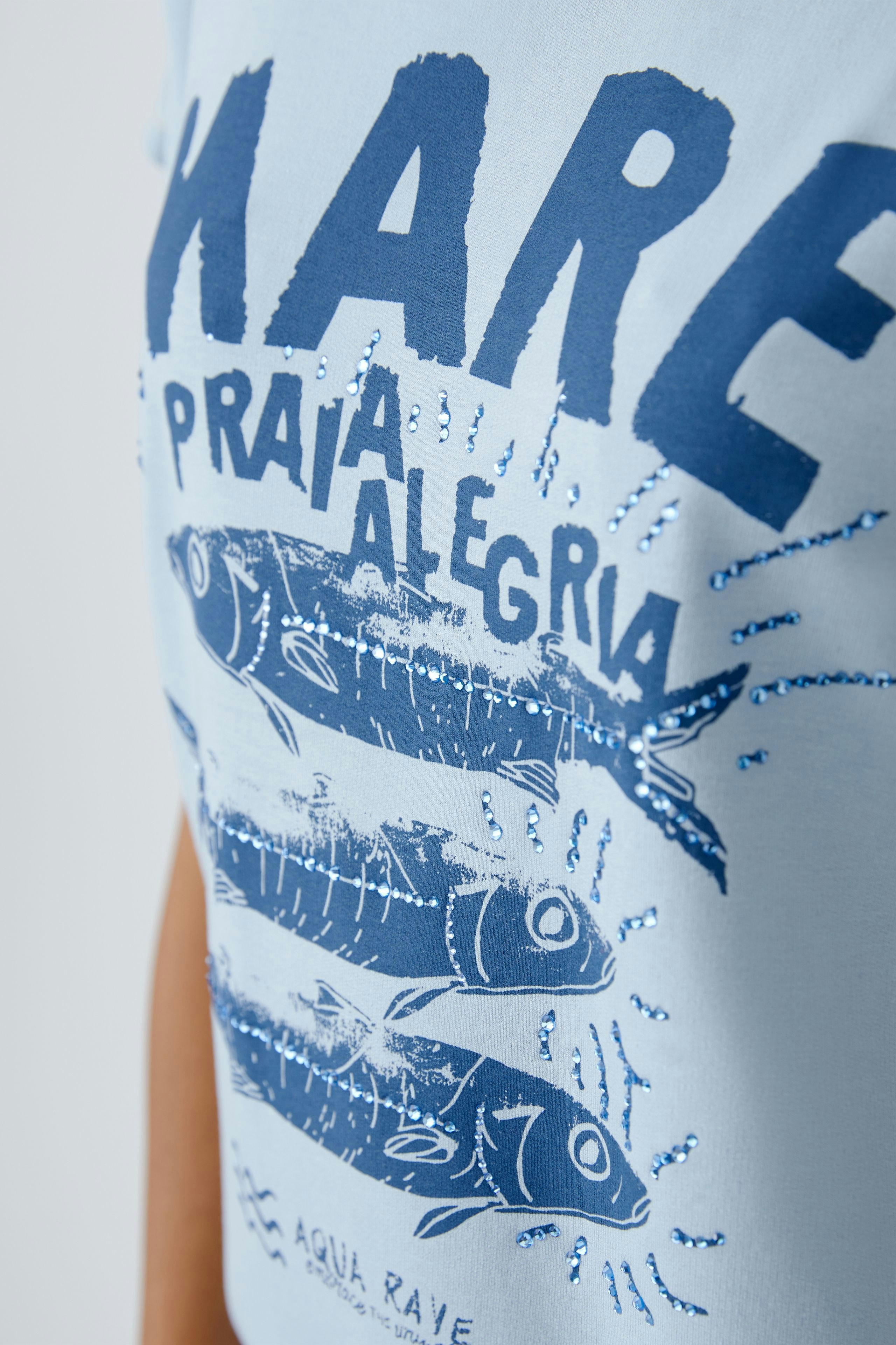 Casual women's T-shirt: A woman in a light blue shirt with a fish graphic, perfect for relaxed outings.