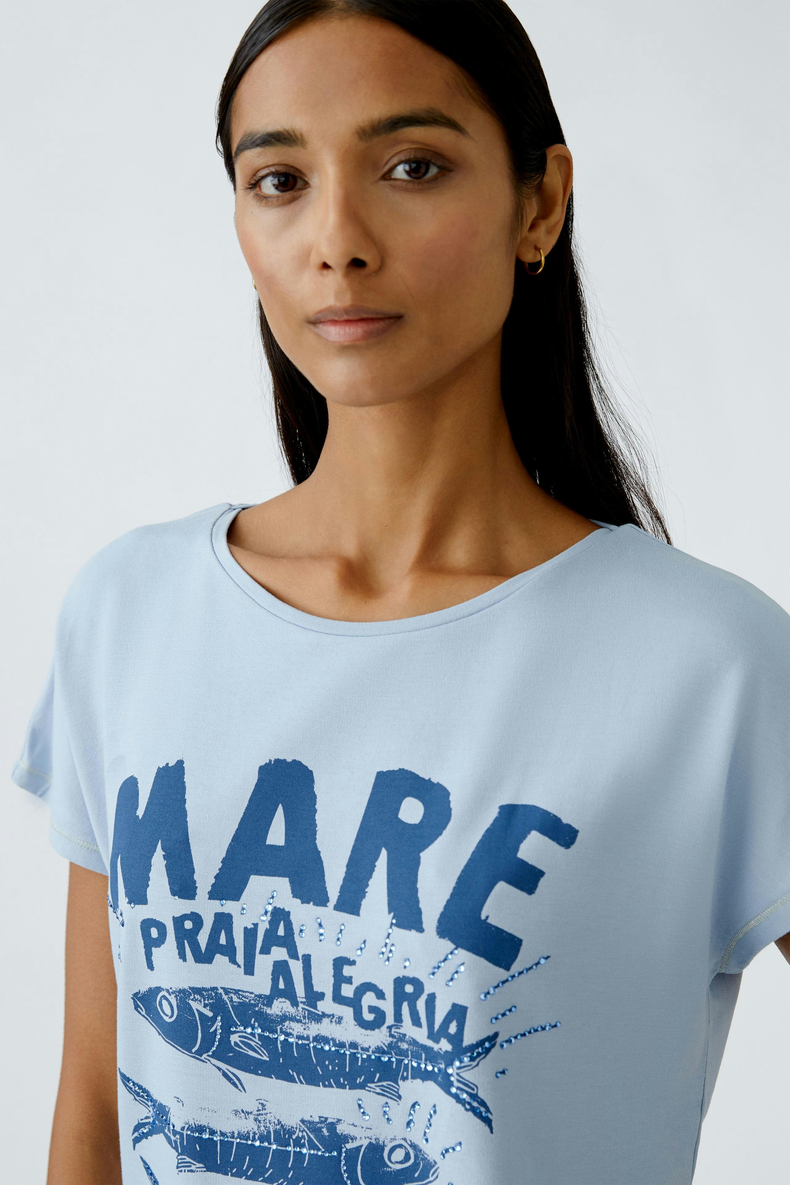 Casual women's T-shirt: Light blue top with a drawstring detail, paired with white pants.