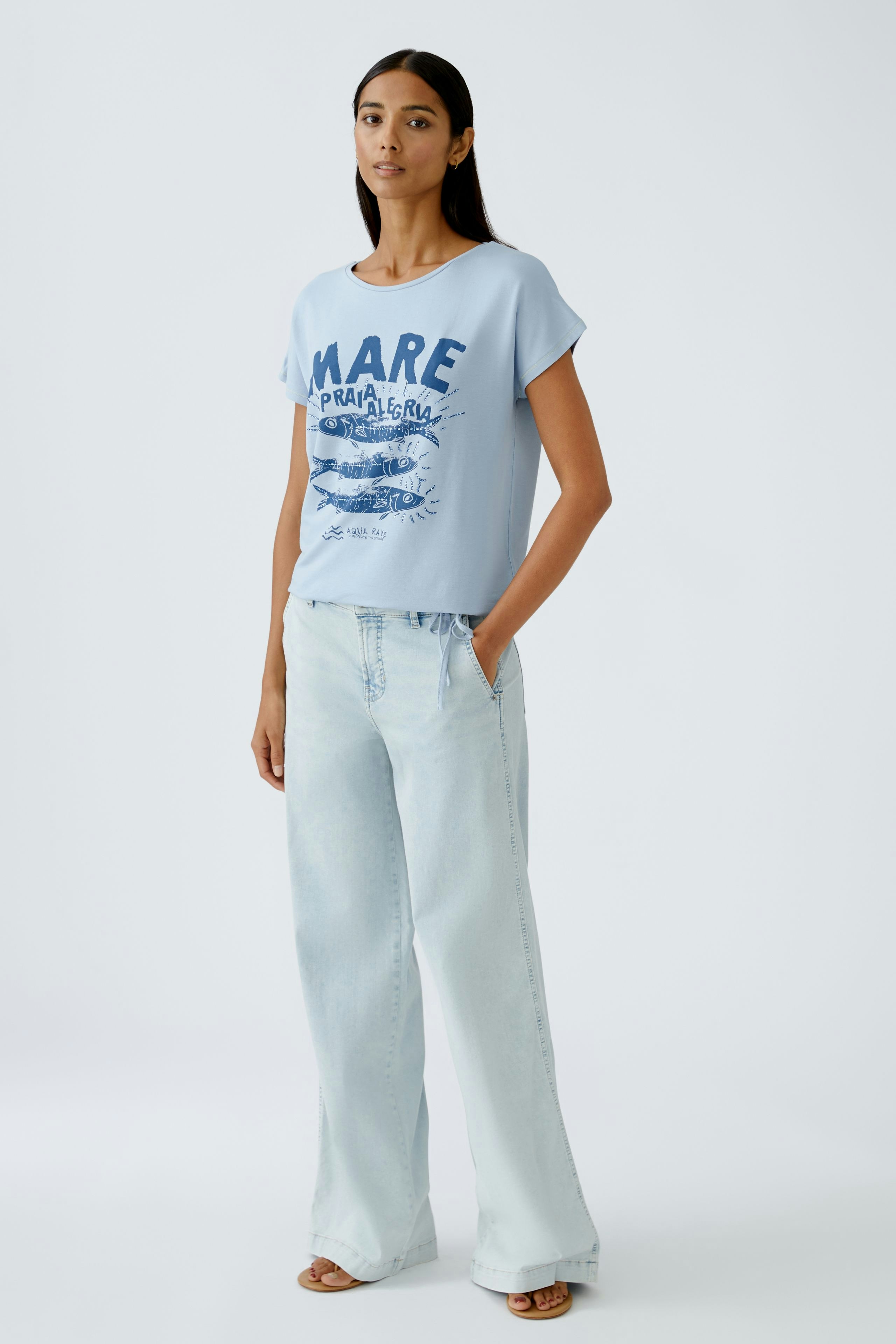 Casual women's T-shirt: Young woman in a light blue tee with a graphic print and relaxed fit.
