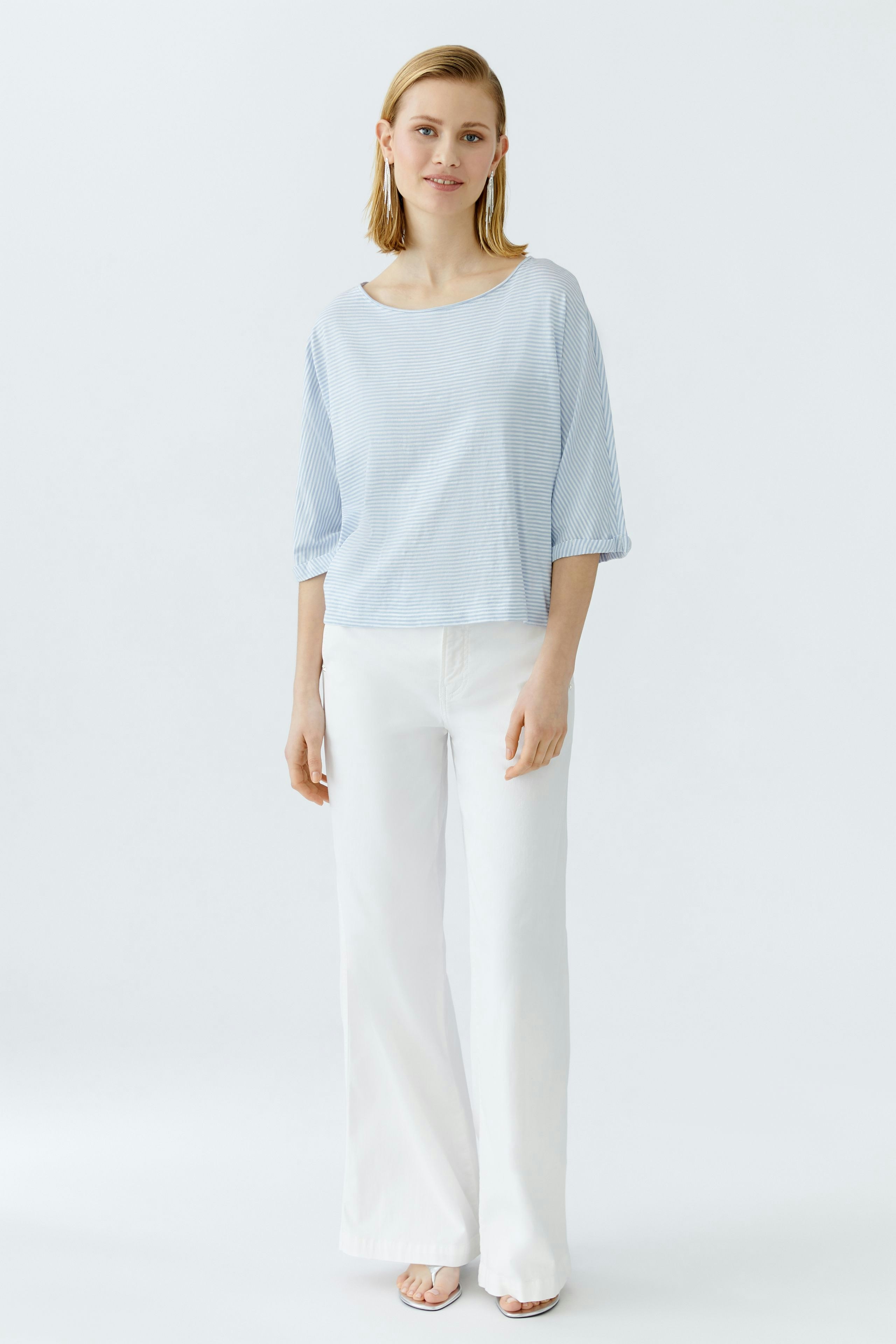 Lässiges Damen-T-Shirt: Junge Frau in einem hellblauen, gestreiften T-Shirt mit lockerer Passform.