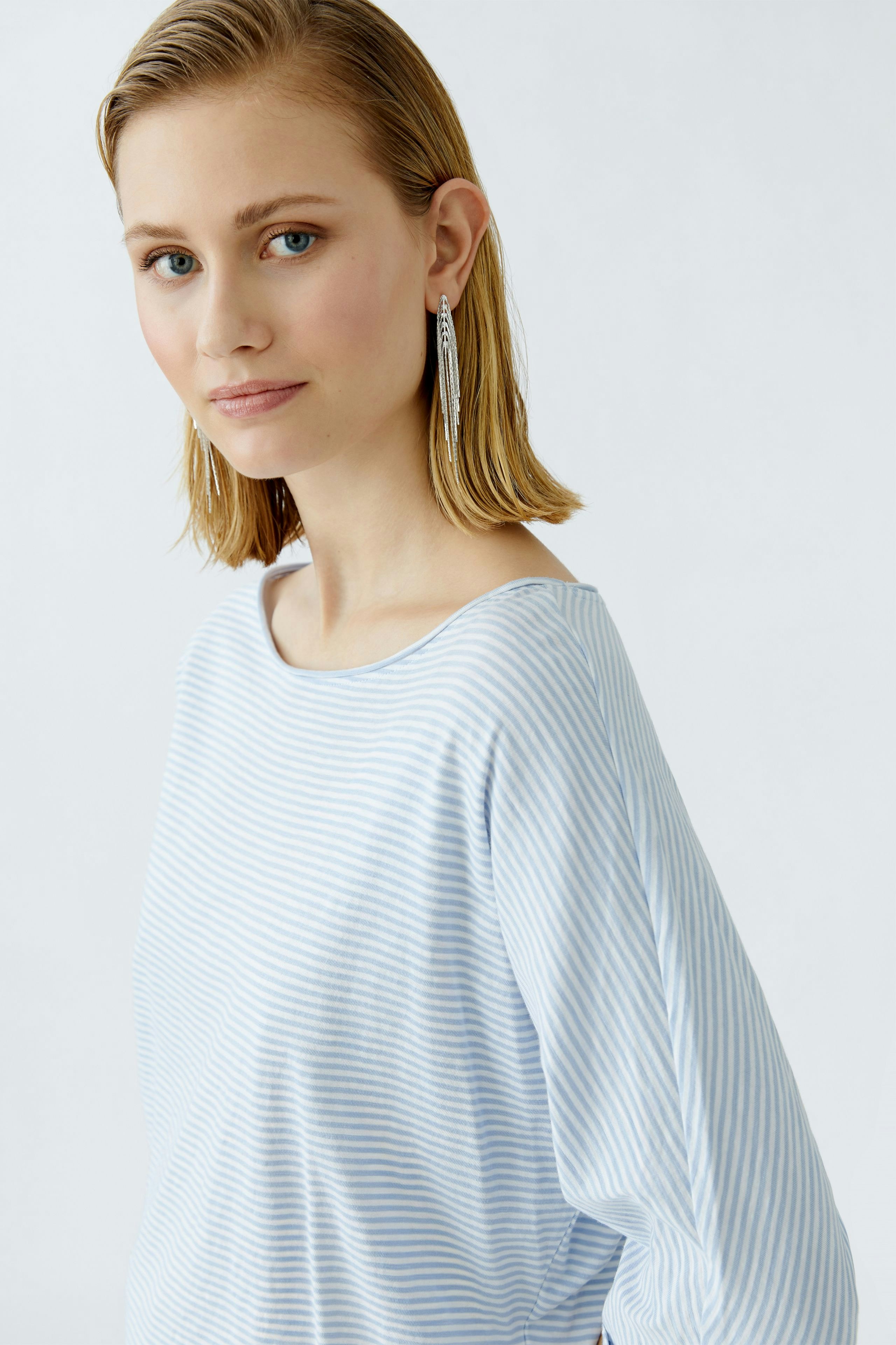 Lässiges Damen-T-Shirt: Junge Frau in gestreiftem, hellblauen T-Shirt mit weitem Ausschnitt.