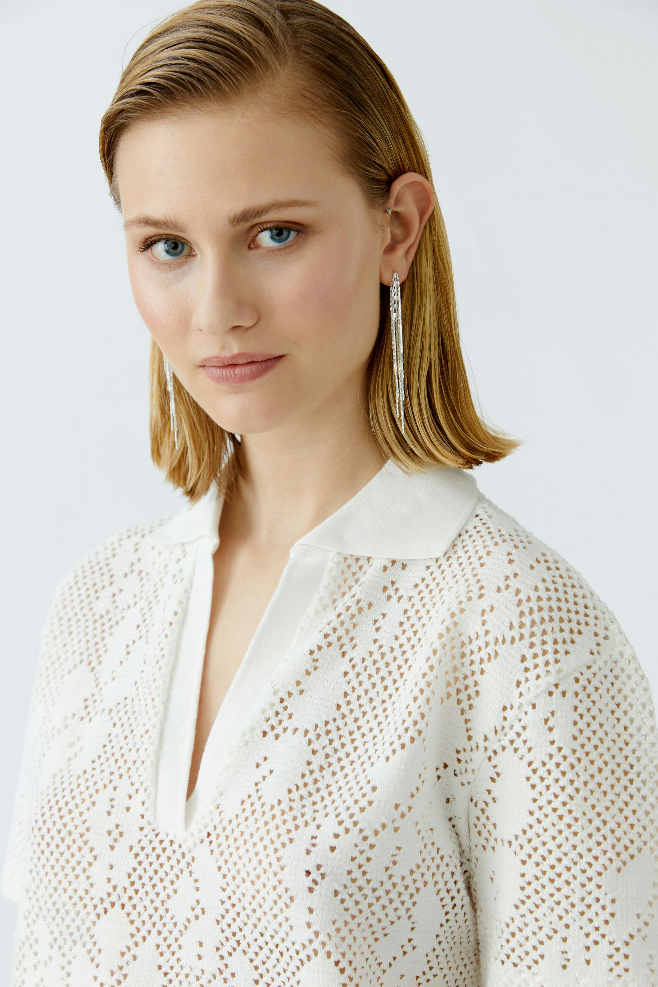 Damen-Poloshirt: Frau in weißem, leichtem Poloshirt mit Kragen und feinem Muster.