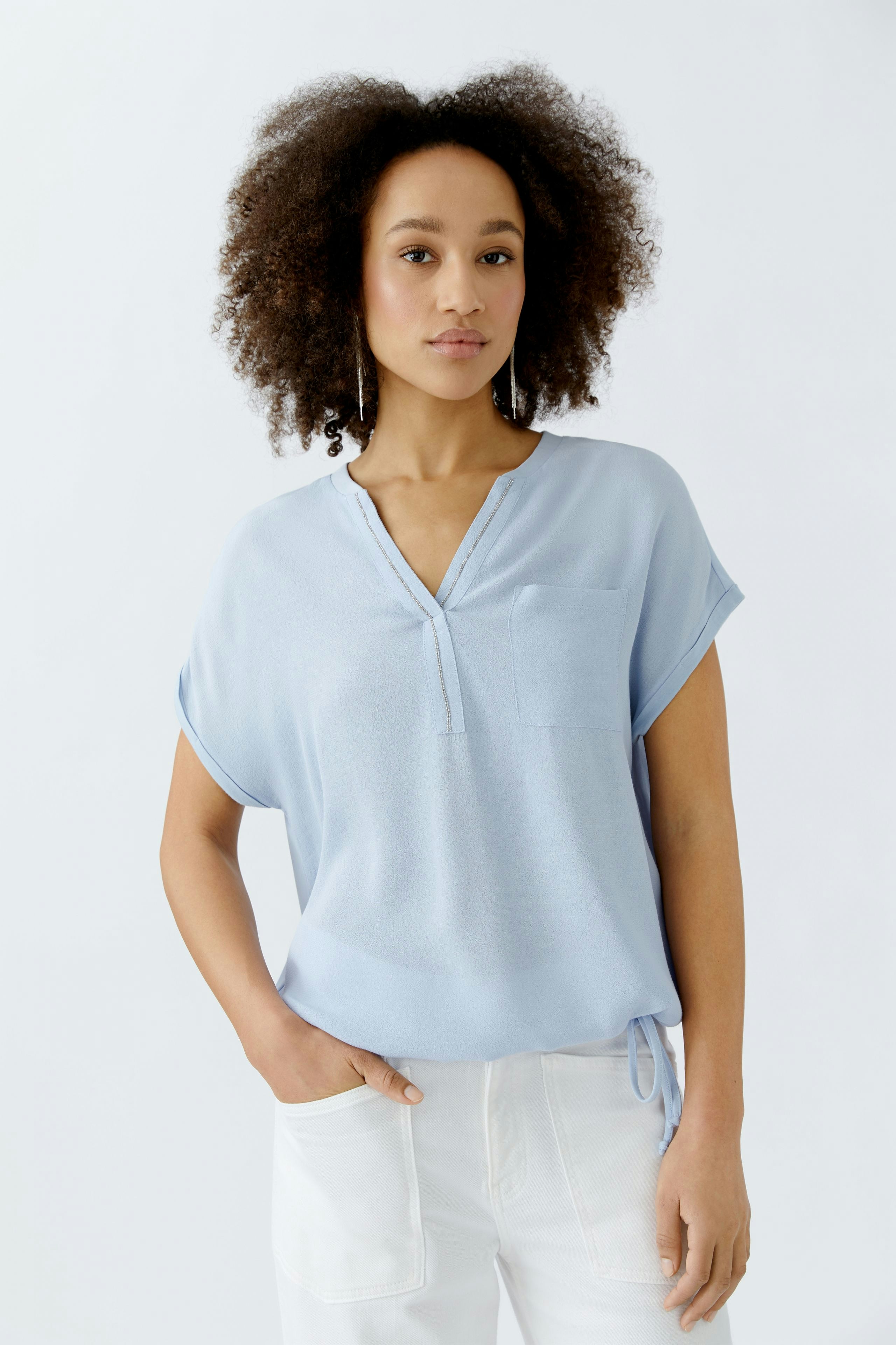 Luftiges Blusenshirt: Frau in hellblauer Bluse mit kurzer Armgestaltung und Brusttasche.