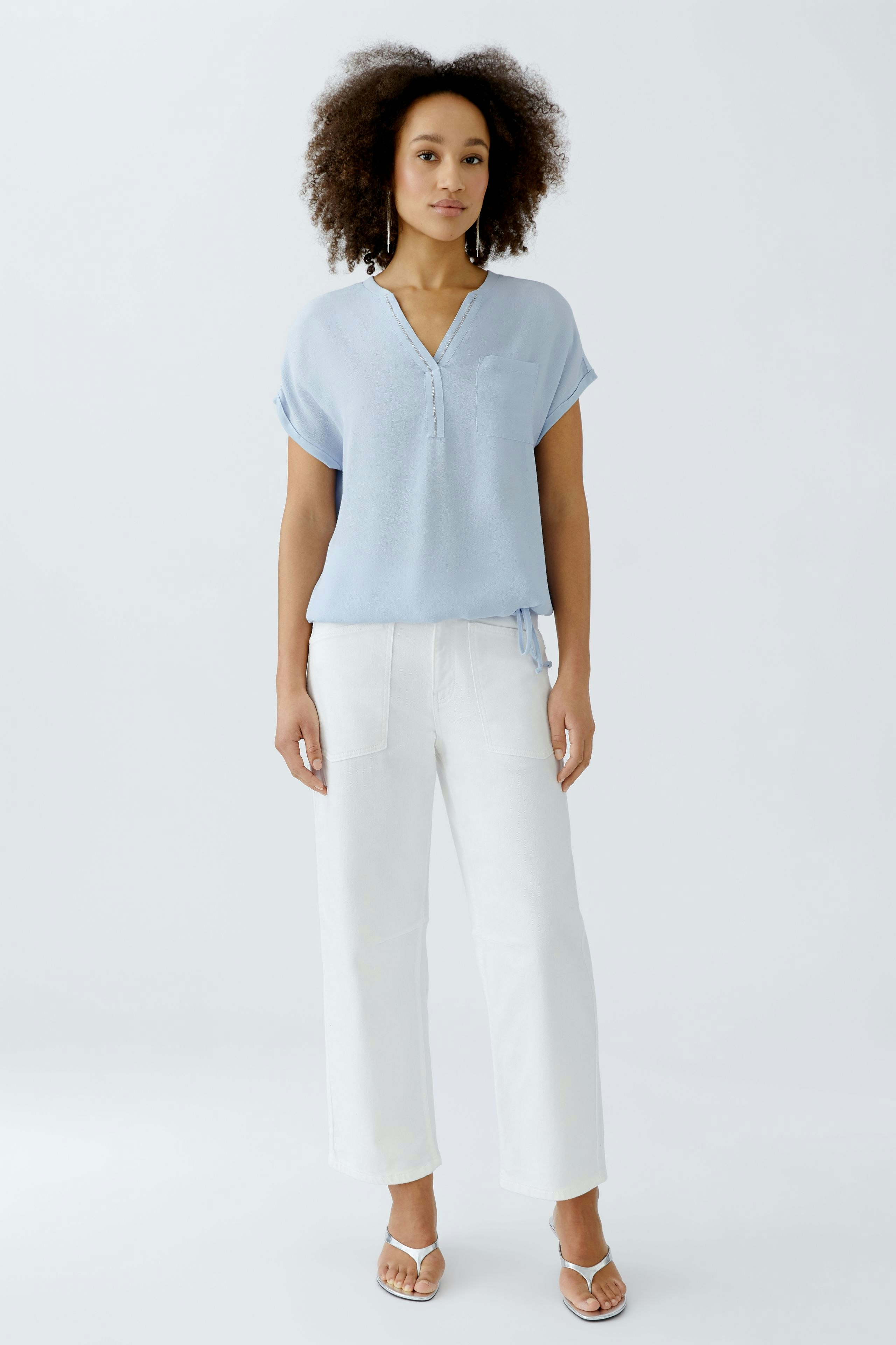 Leichtes Blusenshirt in Hellblau: Frau trägt es mit weißen Hosen und Sandalen.