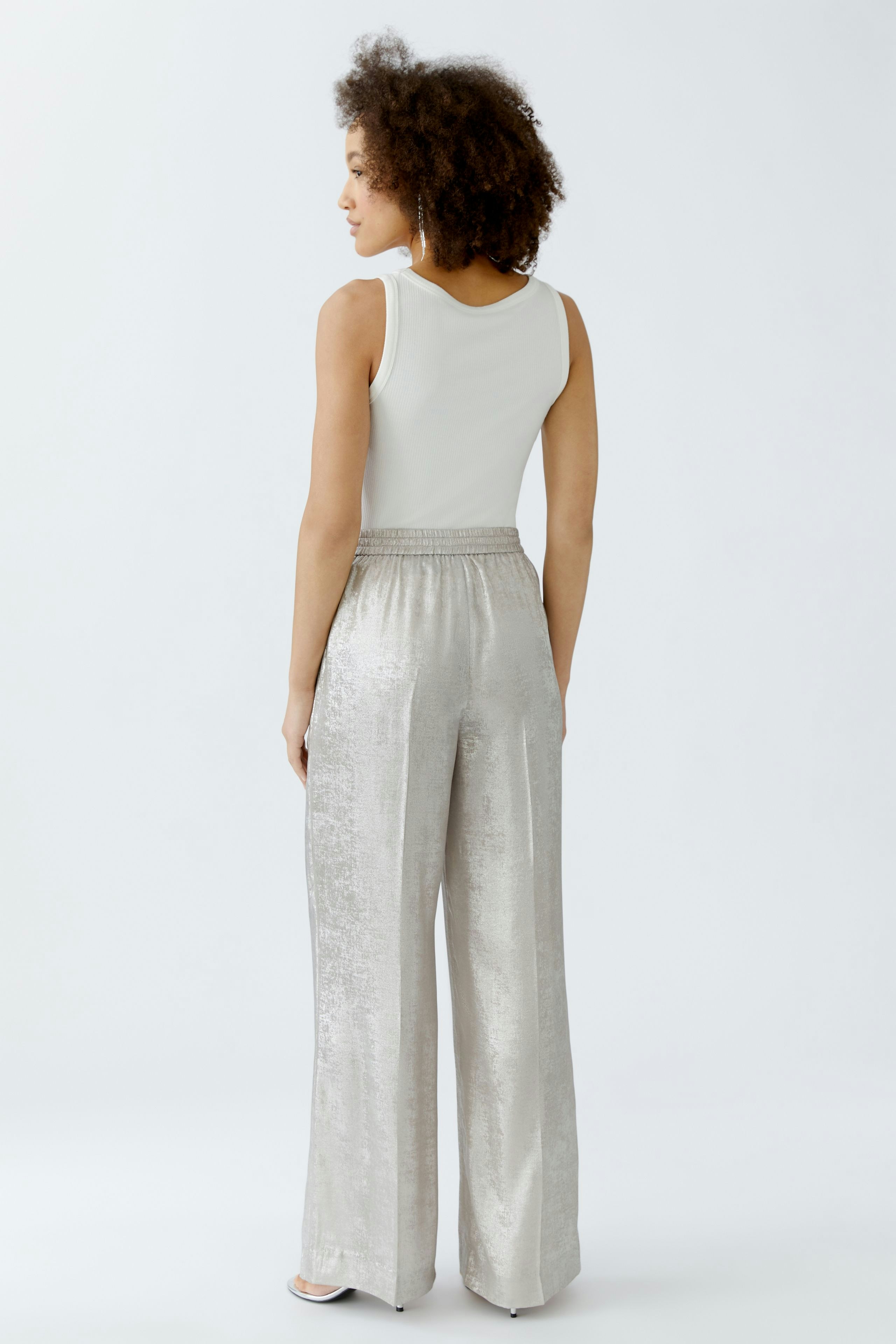 Casual women's Marlene trousers: A woman in shiny silver wide-leg pants, showcasing a relaxed fit.