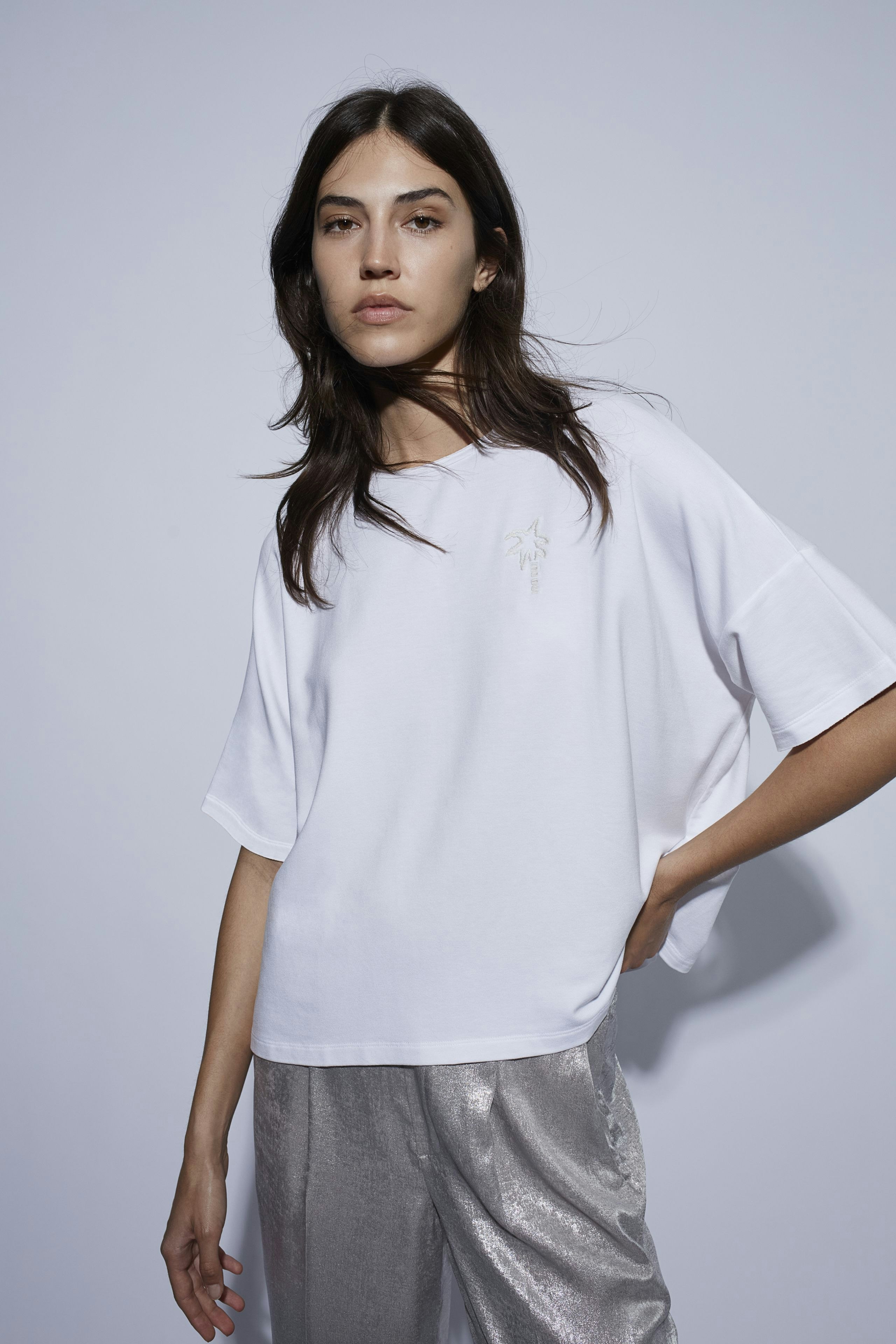 Casual women's Marlene trousers: A woman in white oversized top and shiny silver trousers.