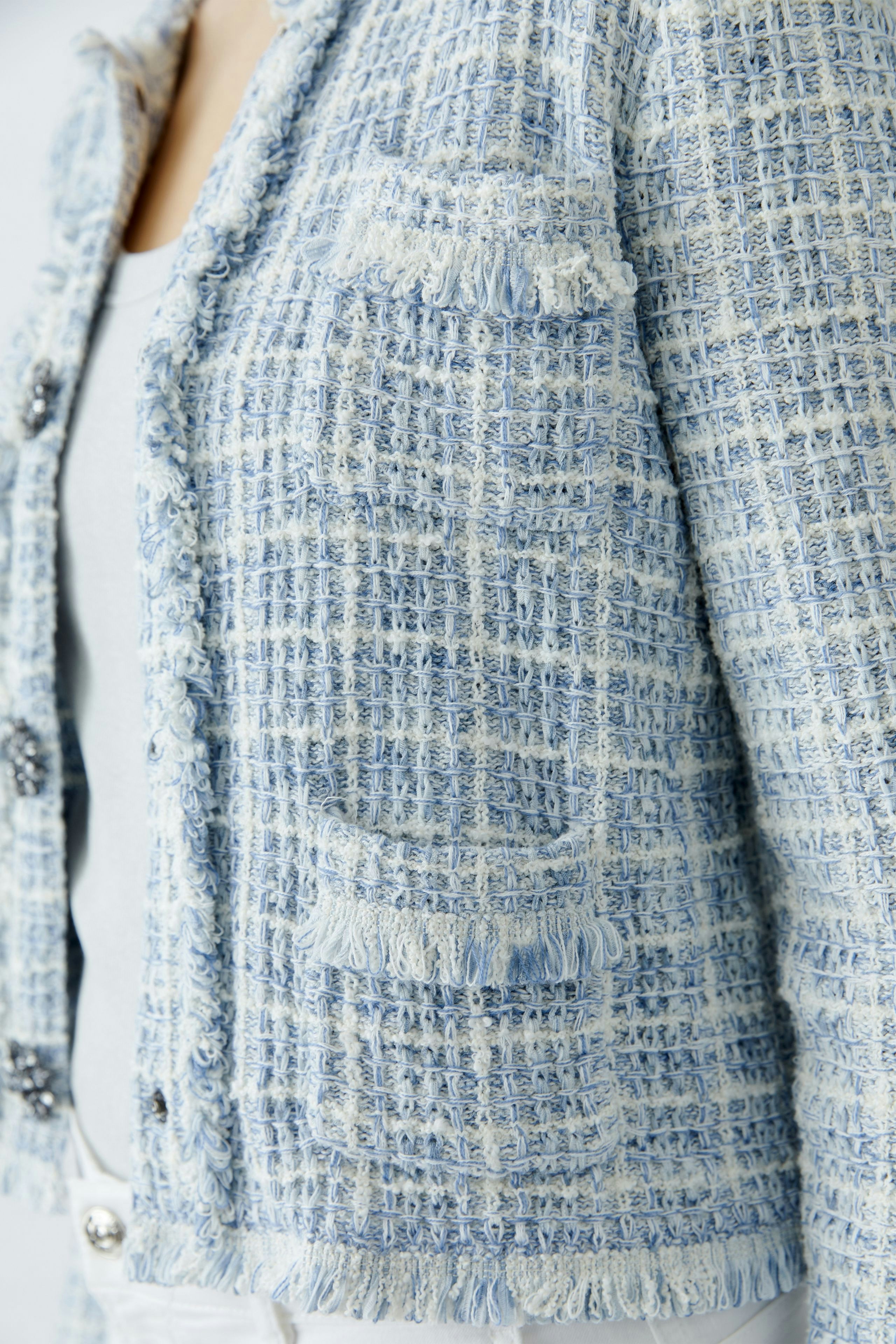 Casual women's cardigan: A woman in a light blue textured cardigan with frayed edges and pockets.