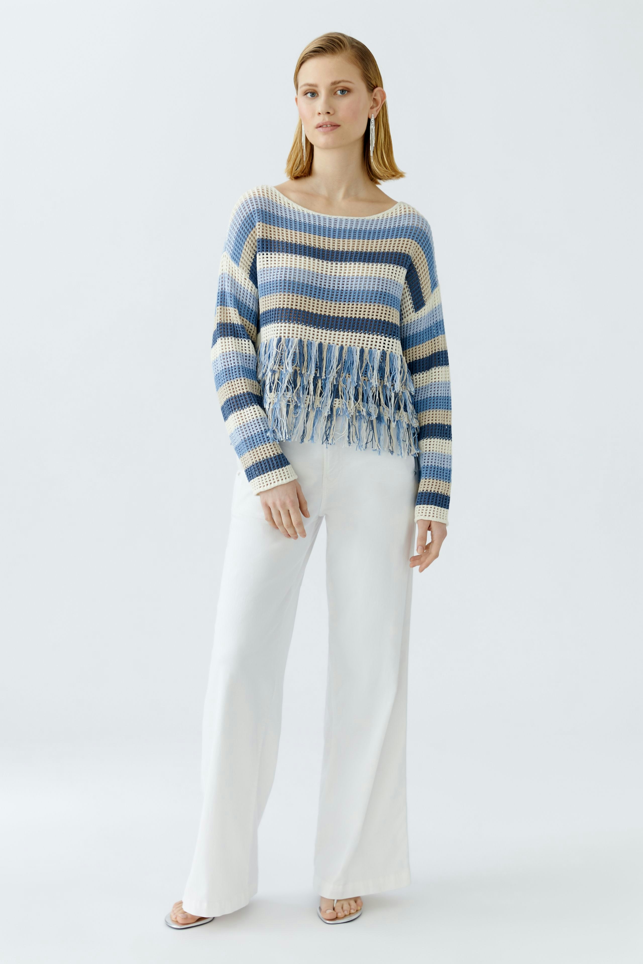 Casual women's pullover: Young woman in a striped pullover with fringe details, paired with wide-leg pants.