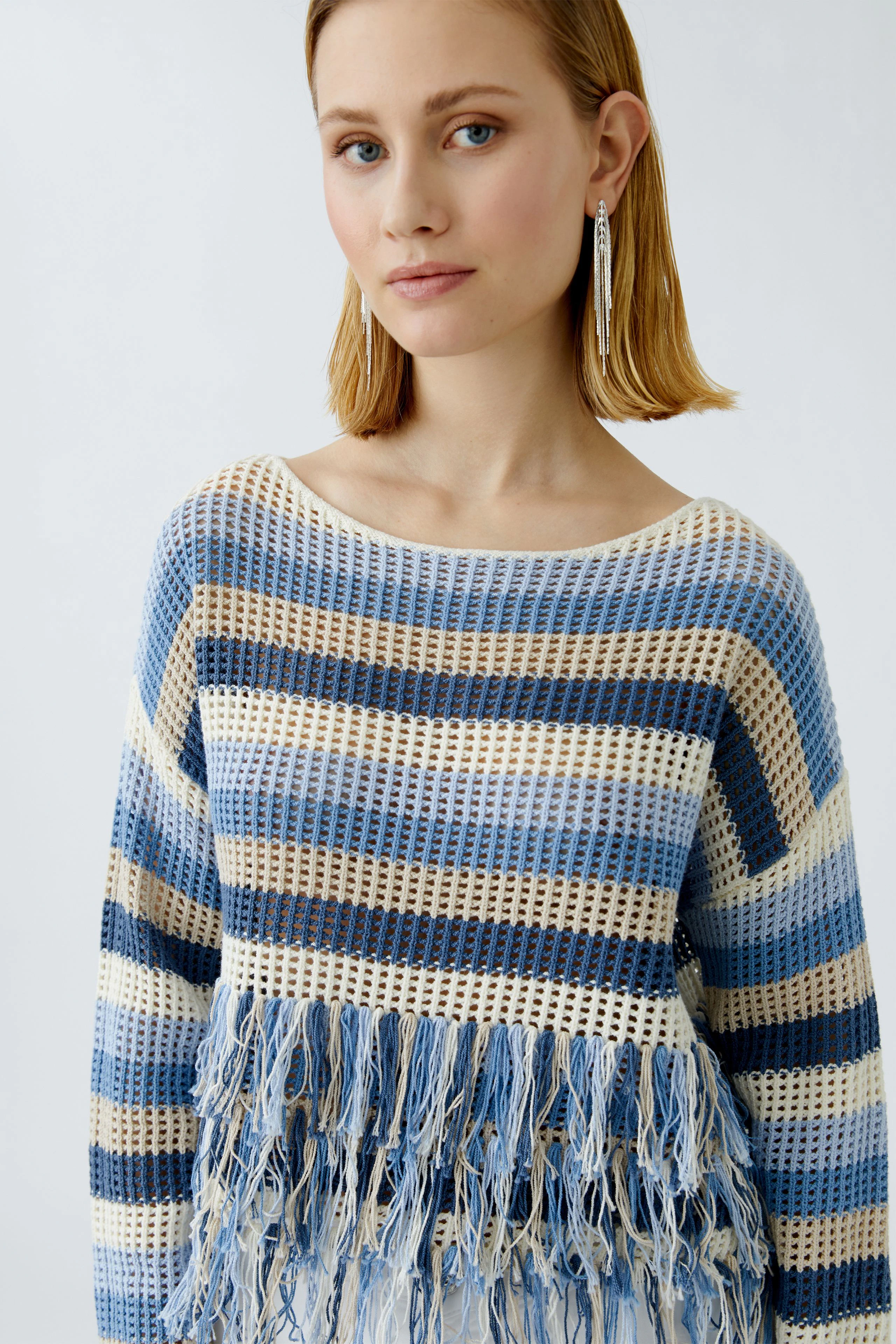 Casual women's pullover: Young woman in a striped pullover with fringes, showcasing a relaxed style.