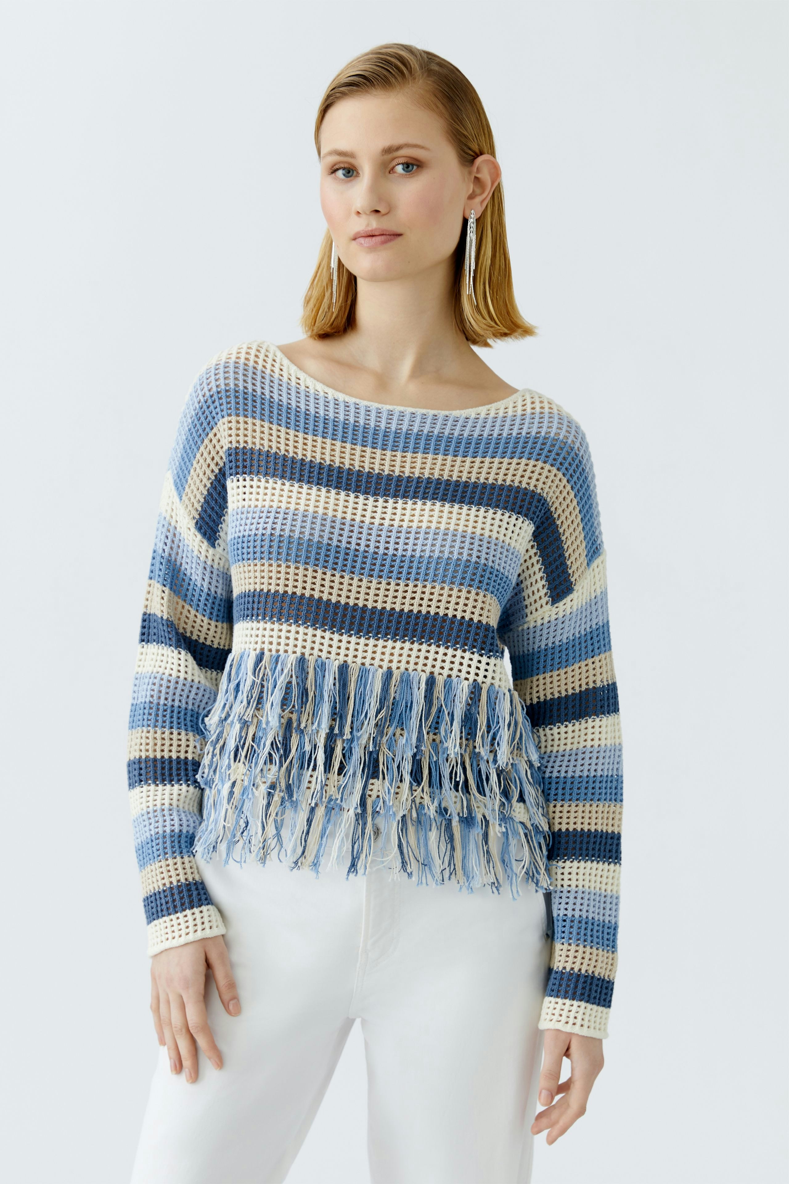 Casual women's pullover: Young woman in a striped pullover with fringes, paired with white pants.