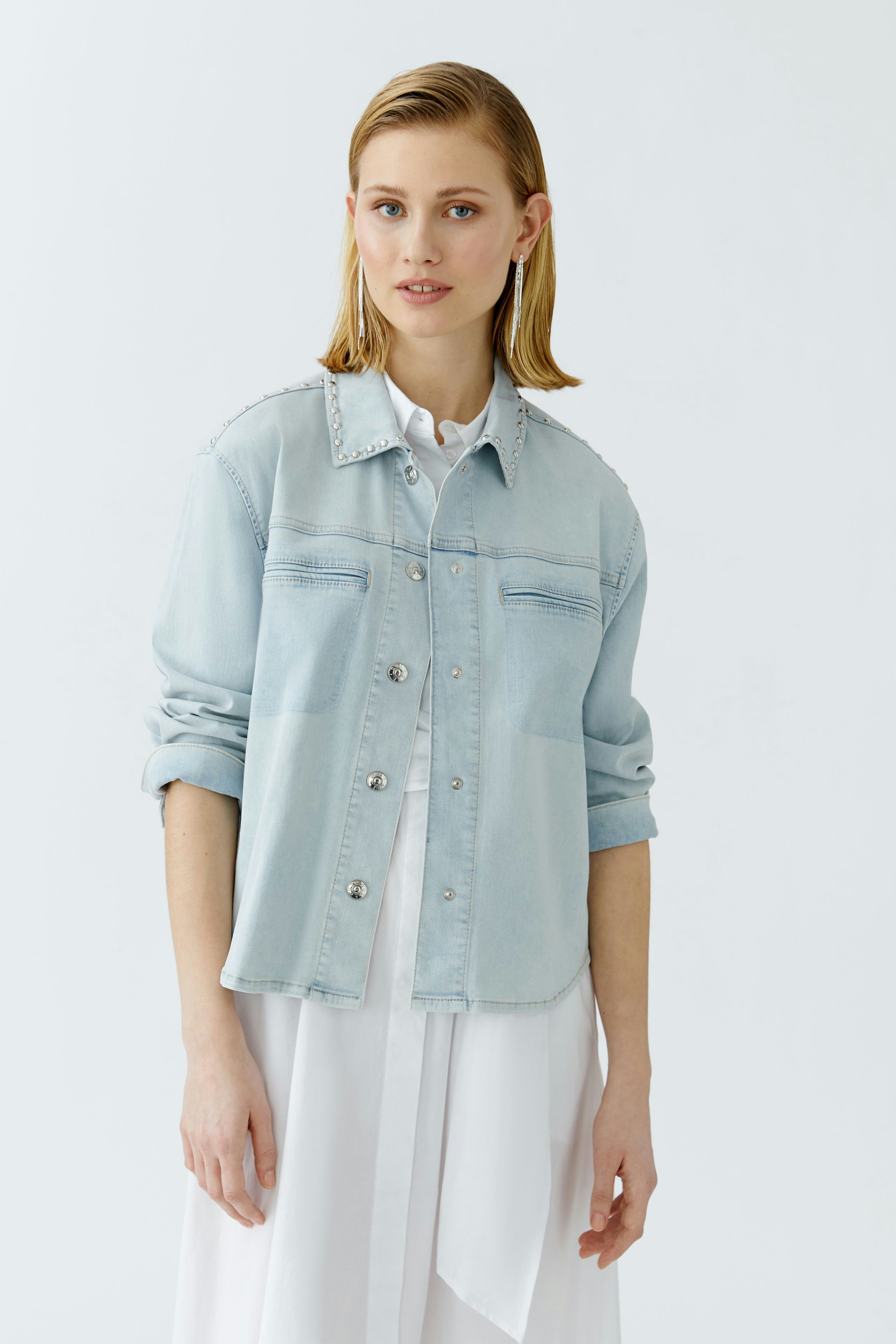 Casual women's denim jacket: A woman in a light blue jacket with button details and rolled-up sleeves.