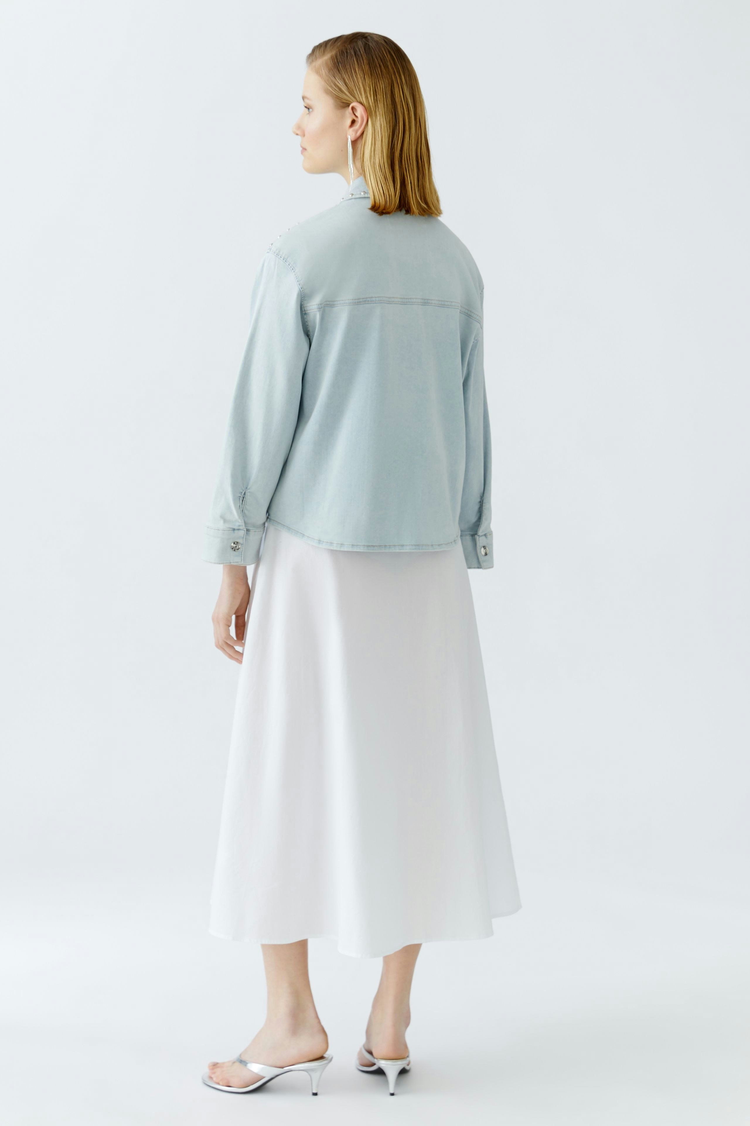Casual women's denim jacket: A woman in a light blue jacket paired with a white skirt.