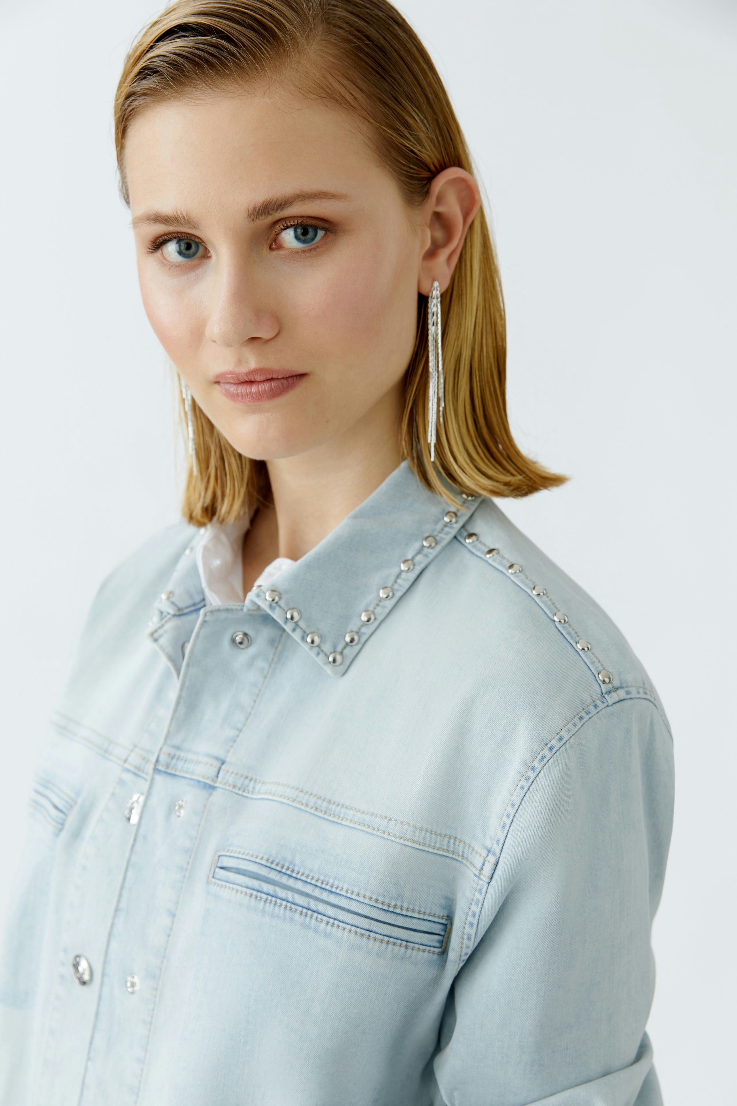 Casual women's denim jacket: Young woman in a light blue jacket with decorative studs.