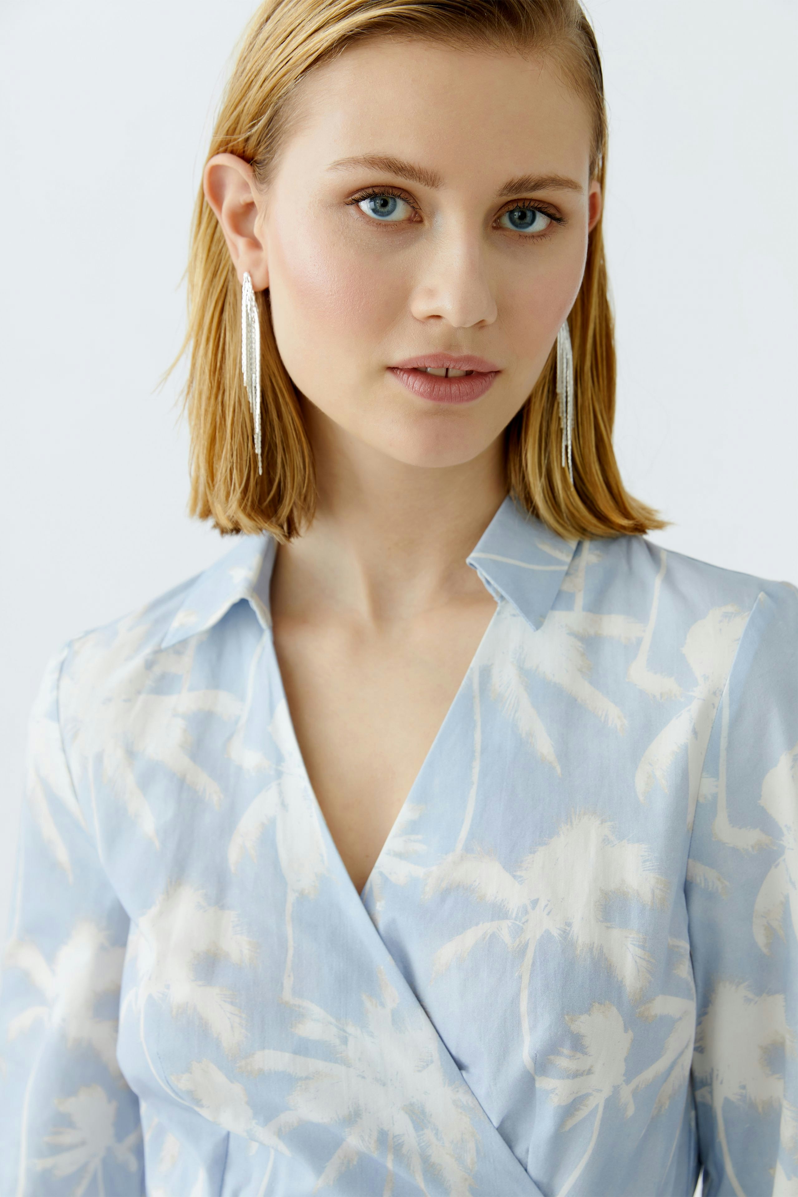 Wickelkleid: Frau mit blauer Bluse und floralem Muster, lässig und modern.