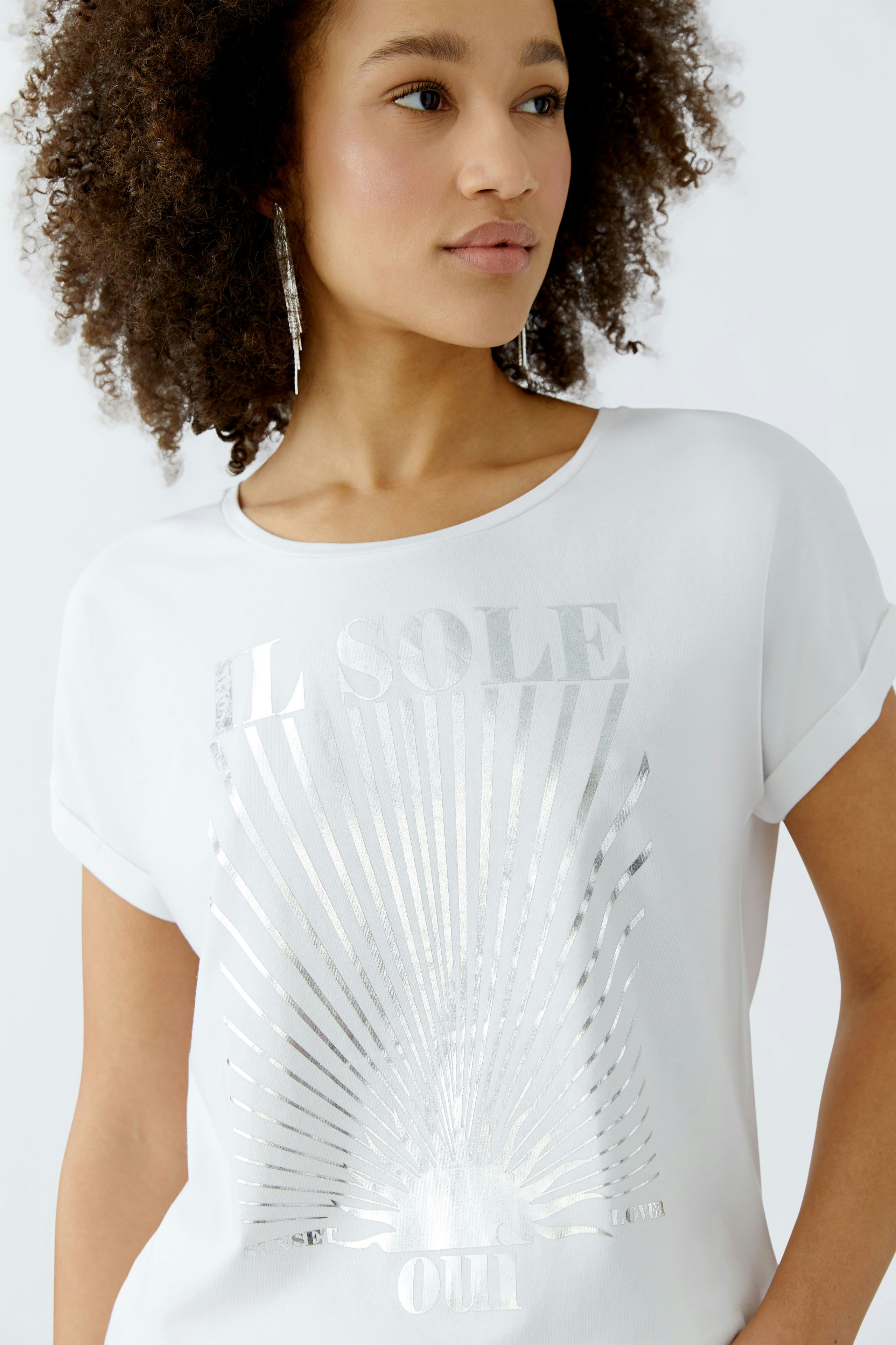 Damen-T-Shirt in Weiß mit glänzendem Print. Junge Frau trägt das Shirt mit lässigem Stil.