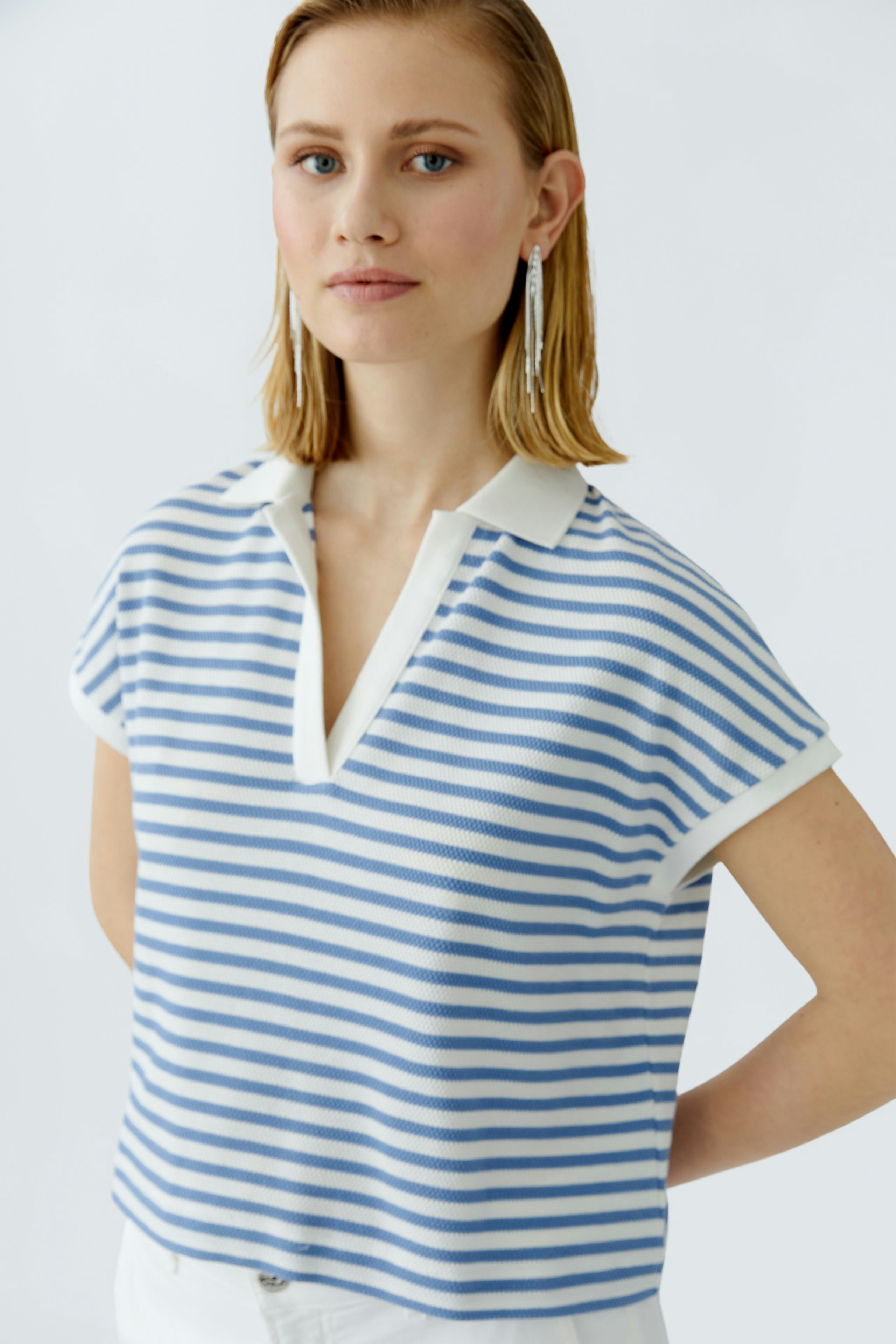 Lässiges Damen-Poloshirt: Frau trägt ein gestreiftes Poloshirt in Blau und Weiß mit Kragen.