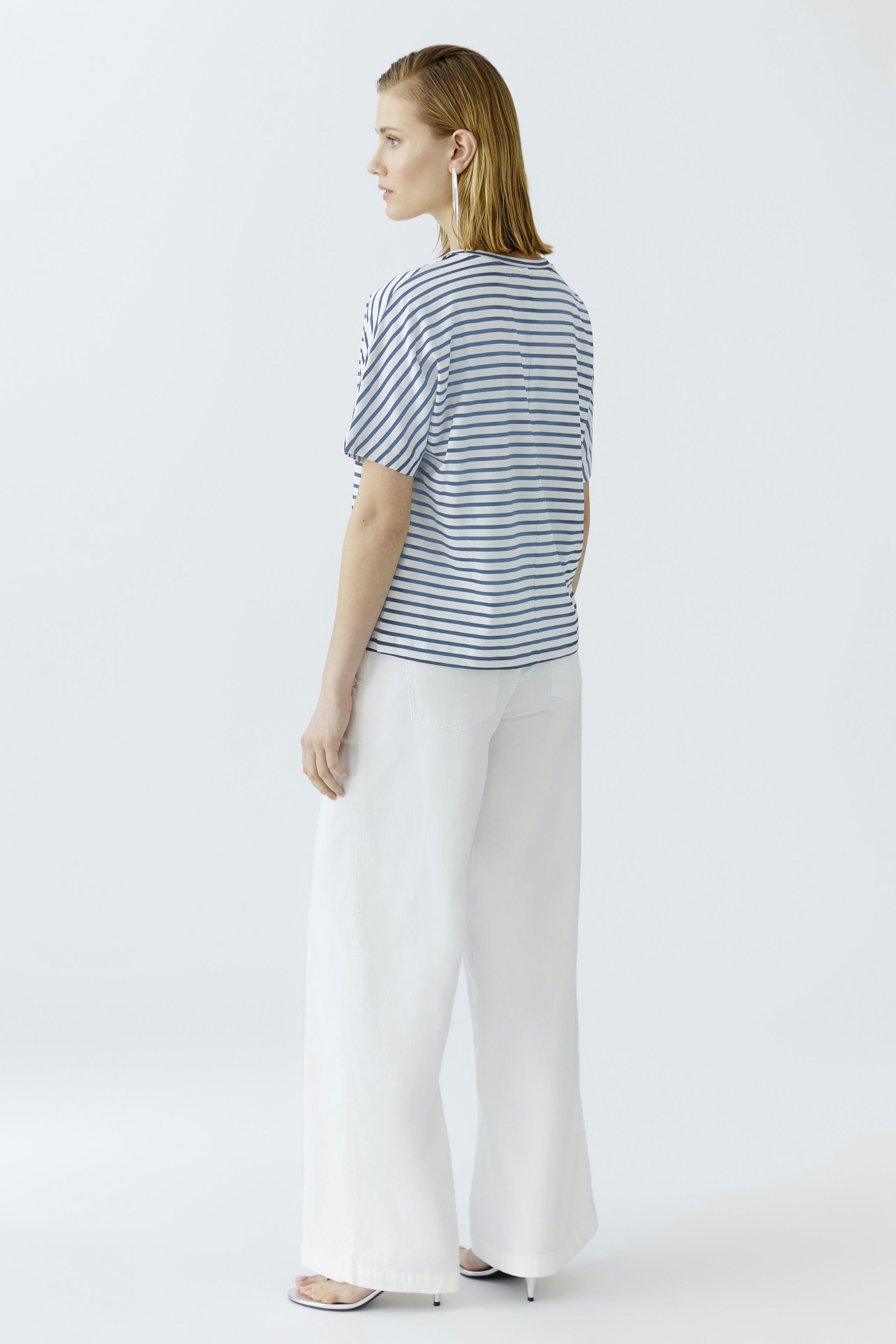 Casual women's T-shirt: Young woman in a striped tee with puff sleeves and white wide-leg pants.