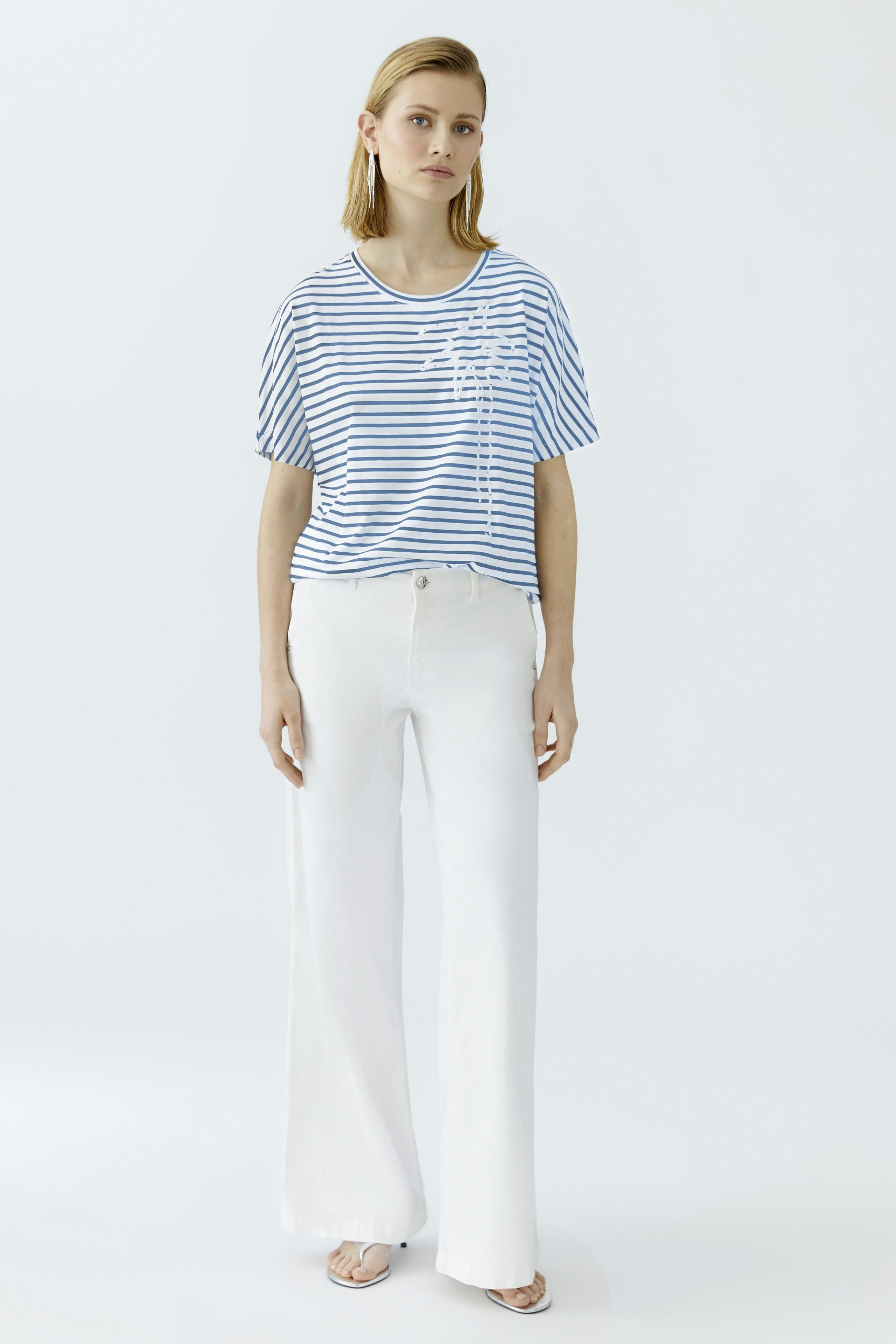 Casual women's T-shirt: Young woman in a striped tee with a relaxed fit and white pants.
