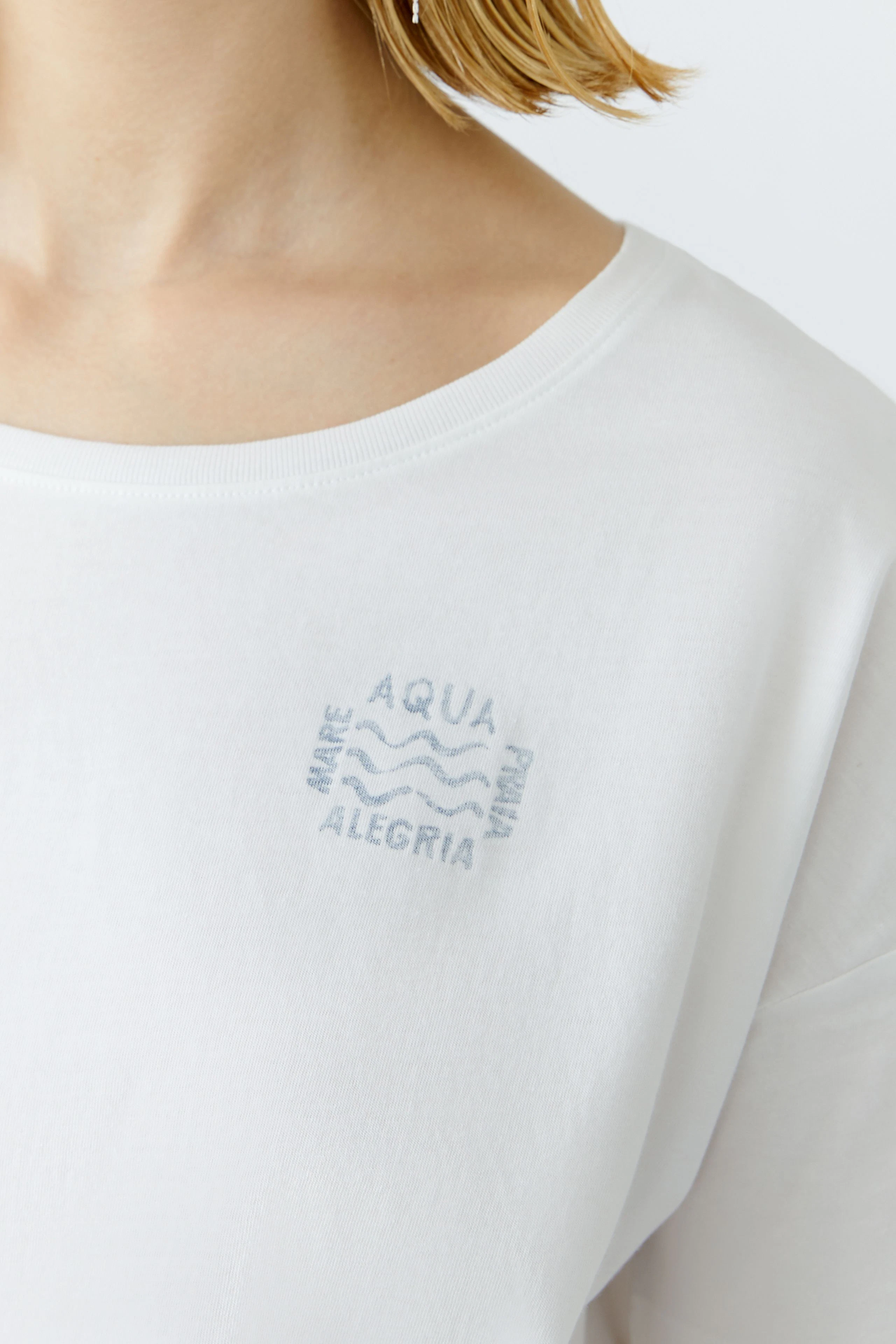 Bequemes Damen-T-Shirt: Frau trägt ein weißes T-Shirt mit dezentem Aufdruck auf der Brust.