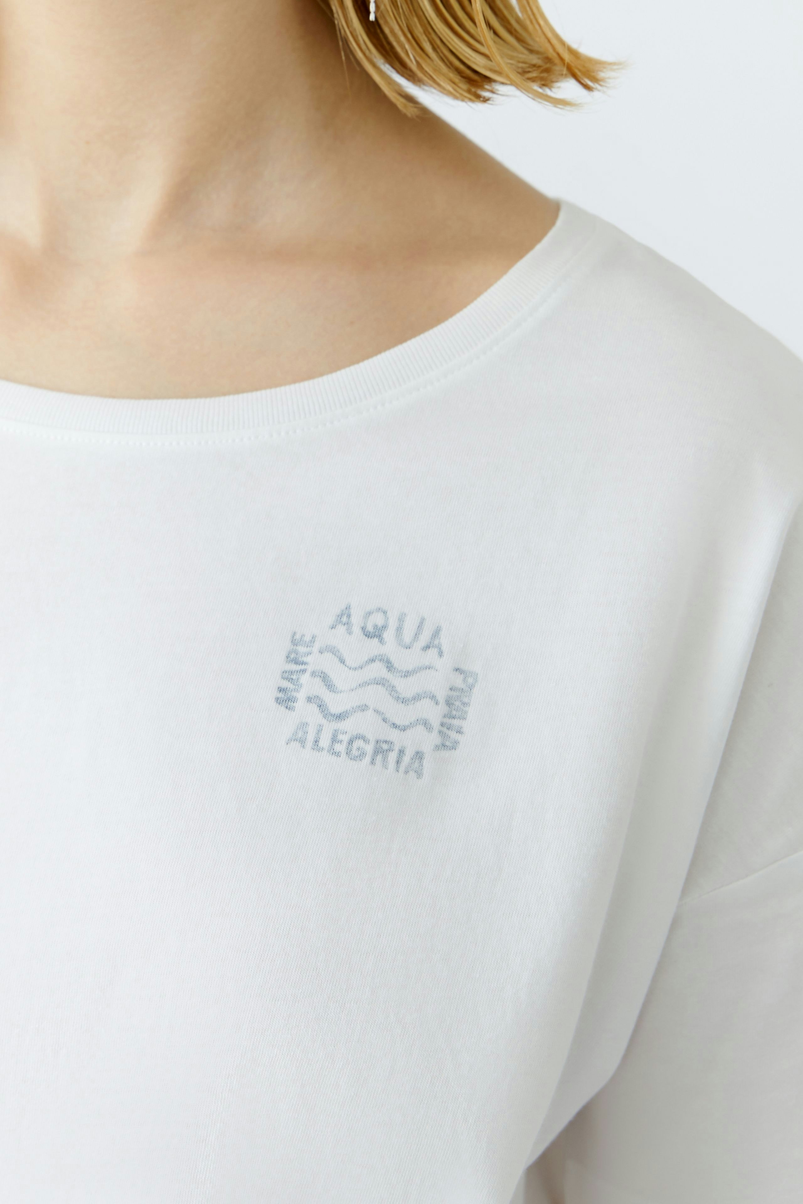 Bequemes Damen-T-Shirt: Frau trägt ein weißes T-Shirt mit dezentem Aufdruck auf der Brust.