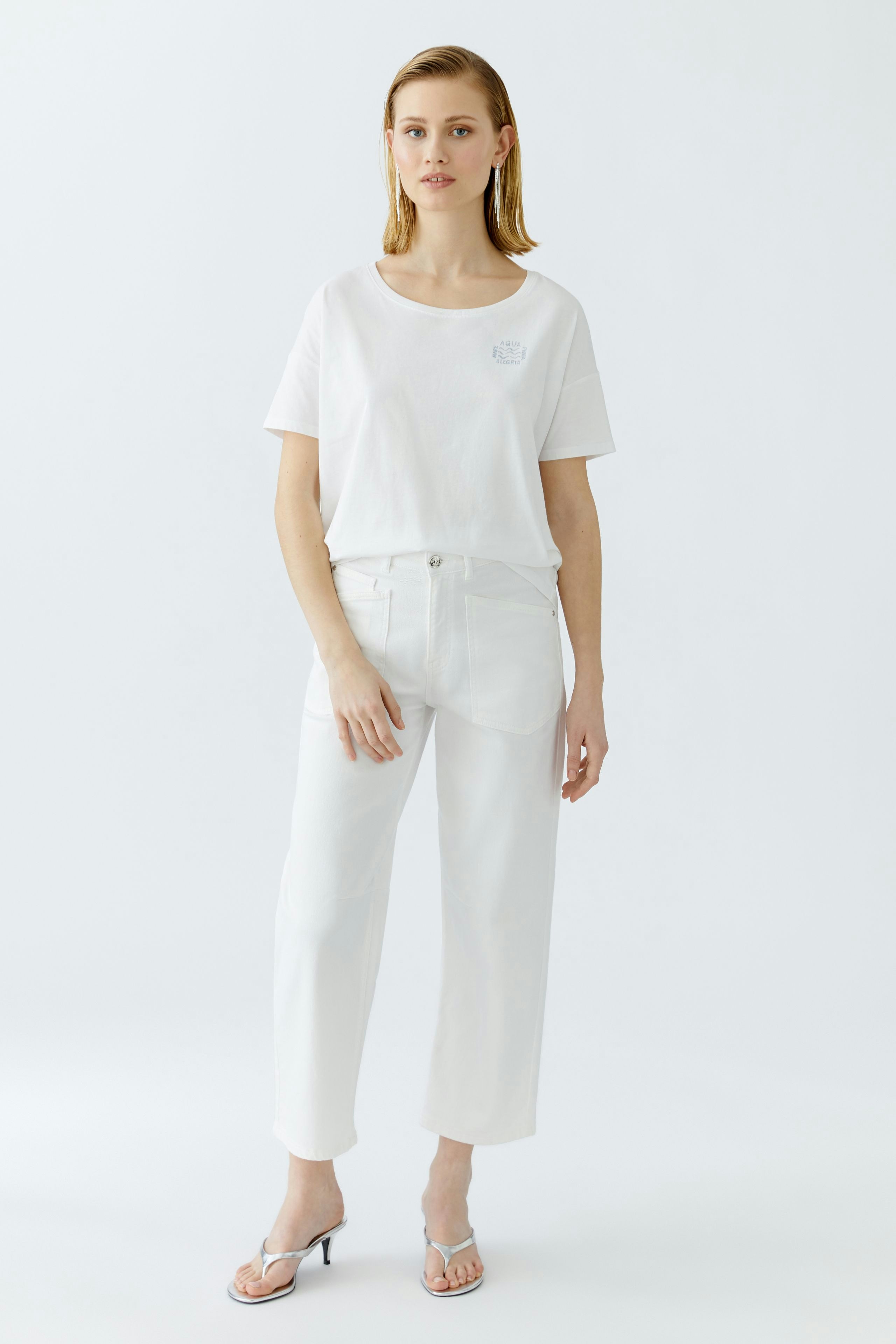 Bequemer Damen-T-Shirt: Junge Frau in einem weißen T-Shirt mit lässigem Schnitt und lockeren Hosen.