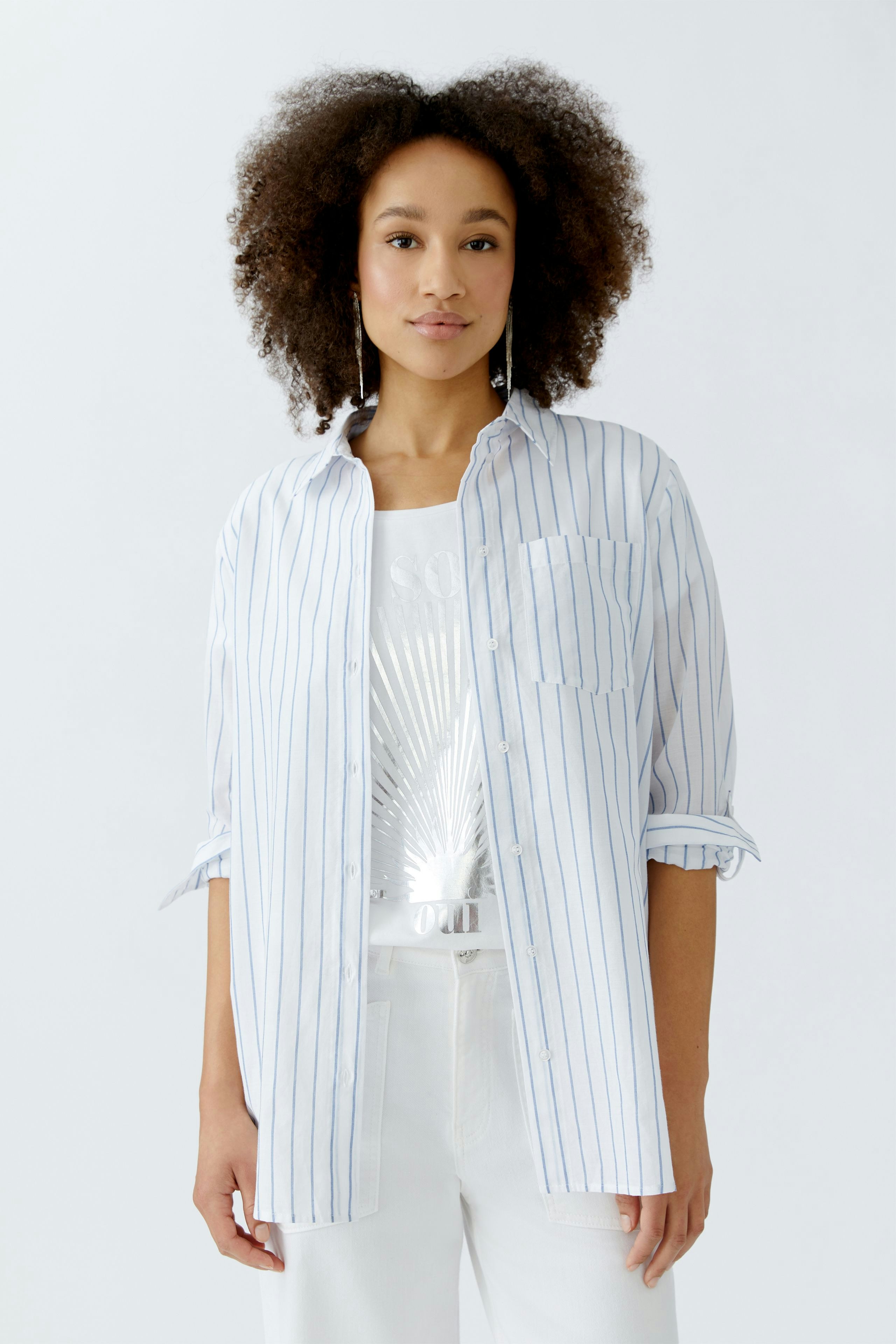 Lässige Damen-Bluse: Frau in gestreifter Bluse mit aufgerollten Ärmeln und lässigem Look.