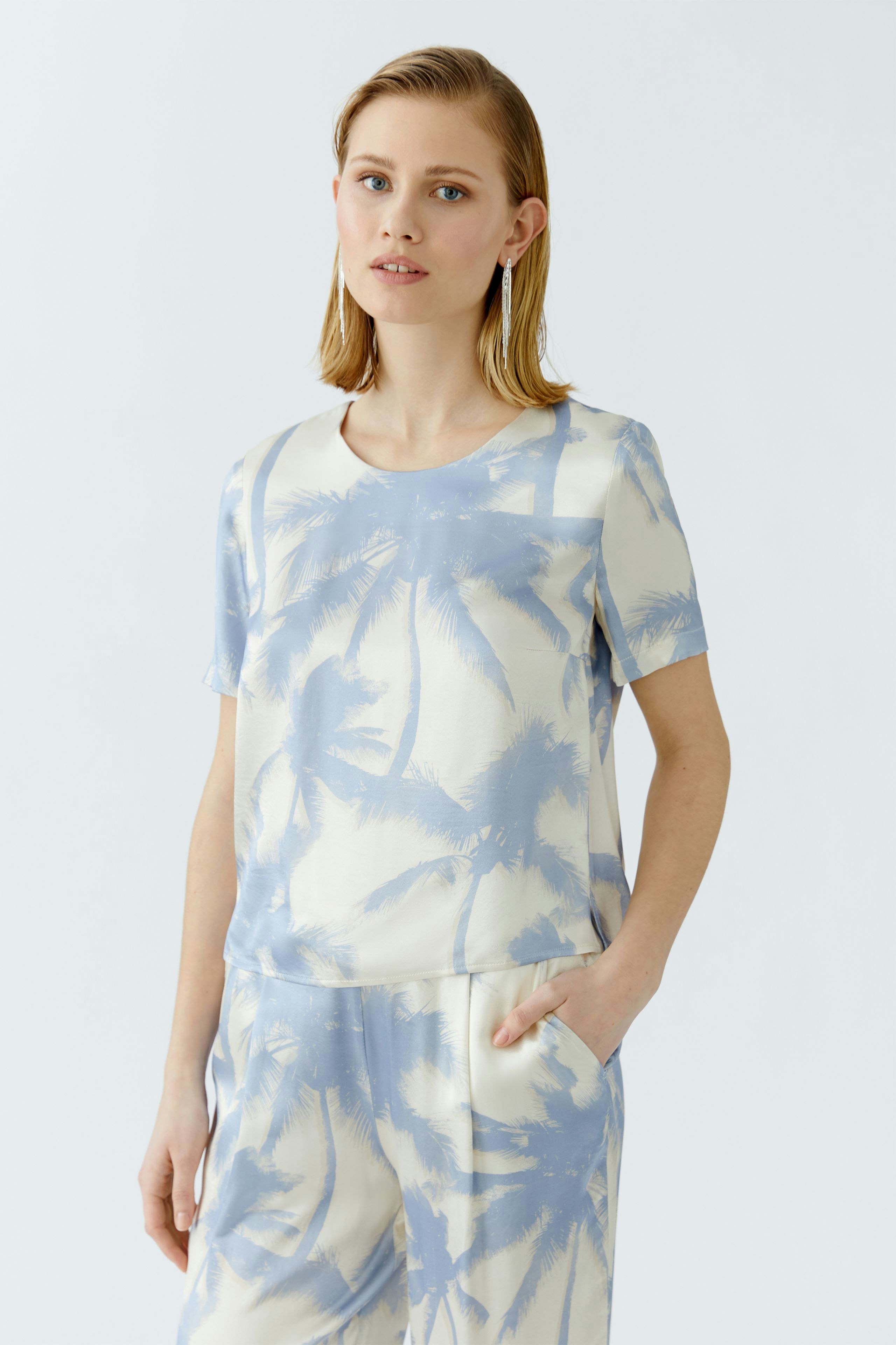 Casual women's blouse: A woman in a light blue palm print blouse with a relaxed fit.