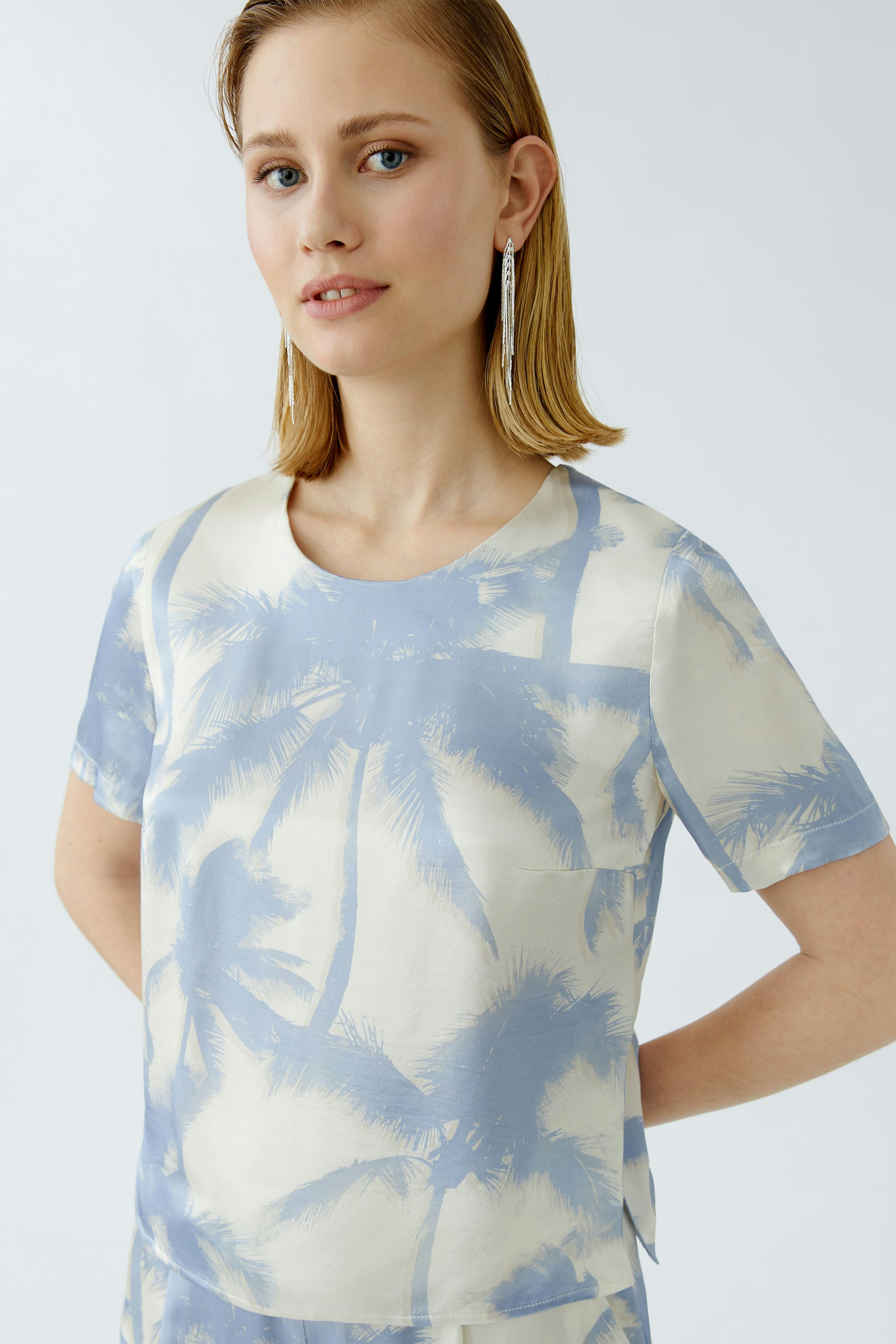 Casual women's blouse: A woman wearing a light blue blouse with palm tree prints, exuding a relaxed vibe.