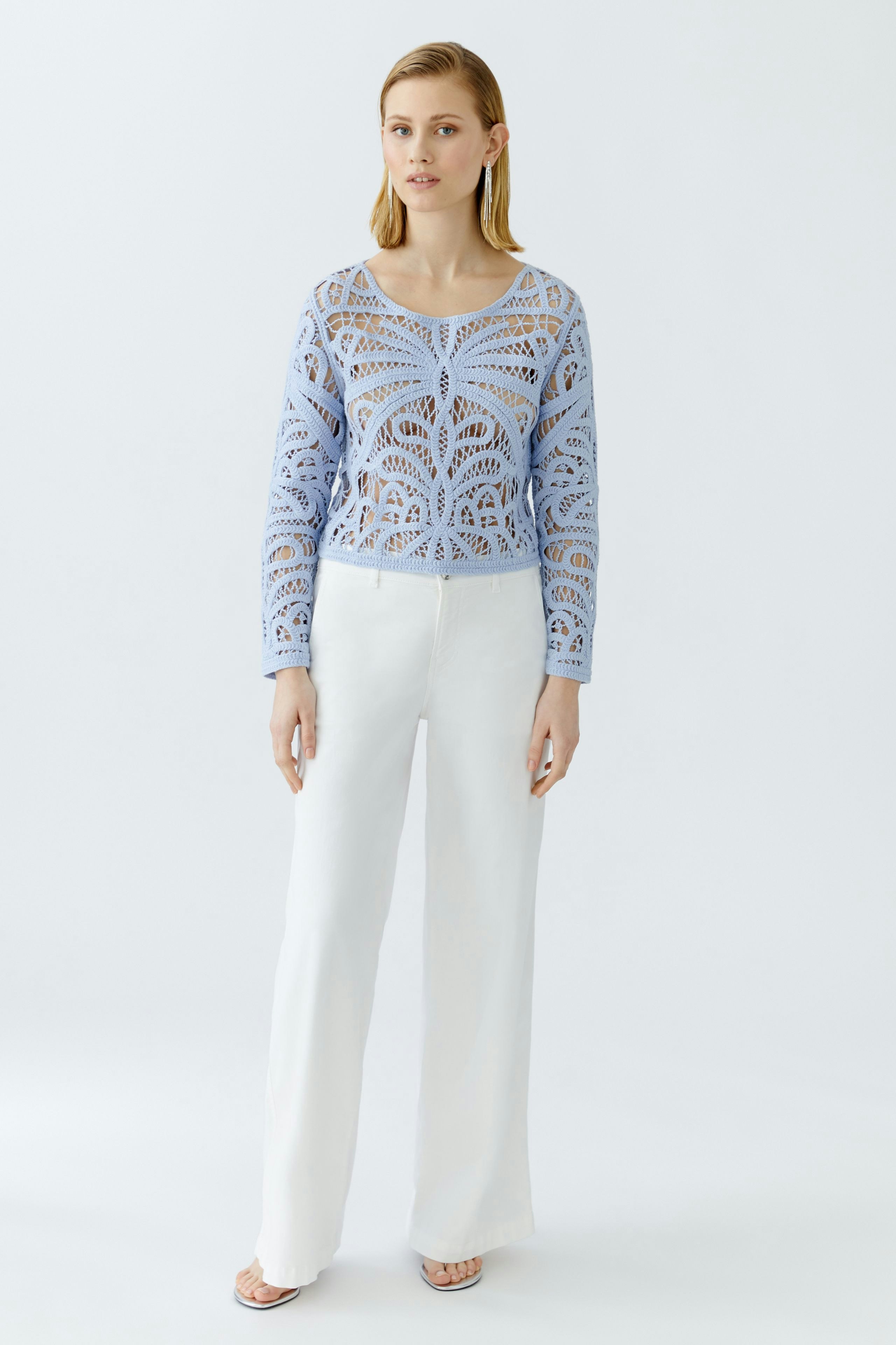 Damen-Pullover: Junge Frau in hellblauem, leichtem Strickpullover mit filigranem Muster und weißen Hosen.