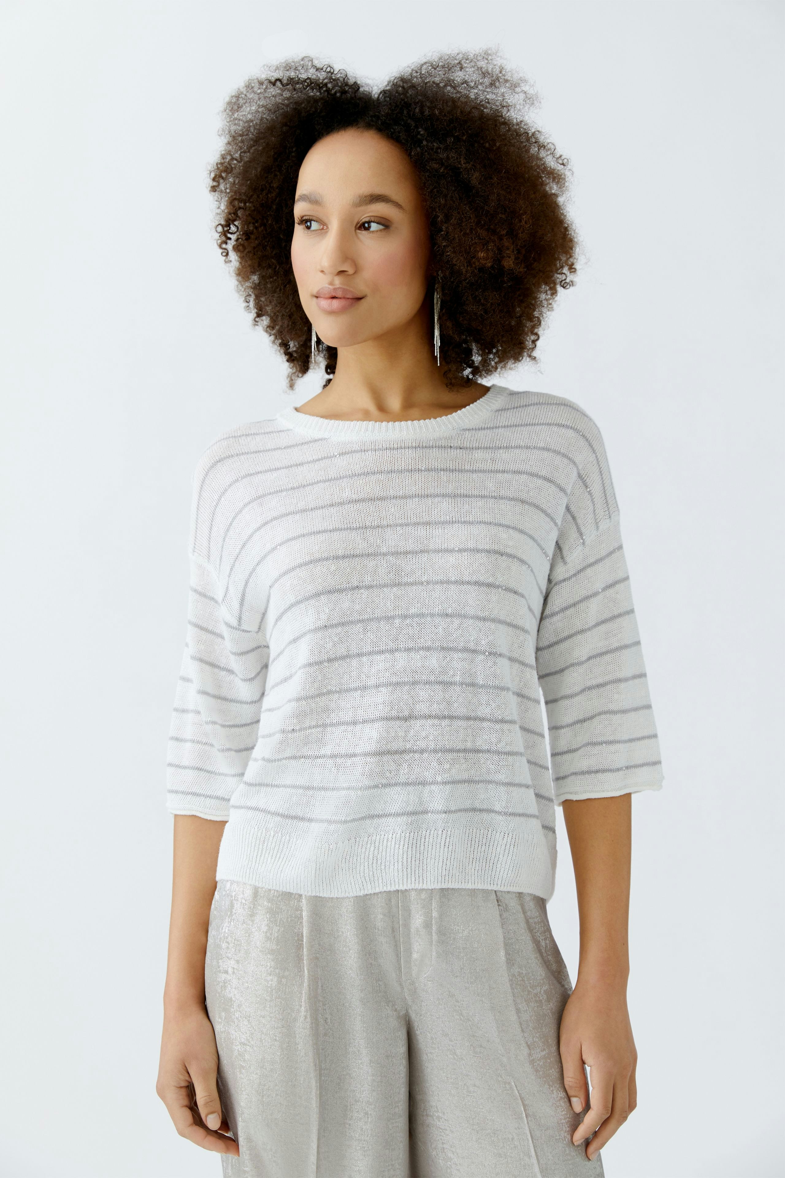 Damen-Pullover: Frau trägt einen gestreiften, lässigen Pullover in Weiß und Grau.