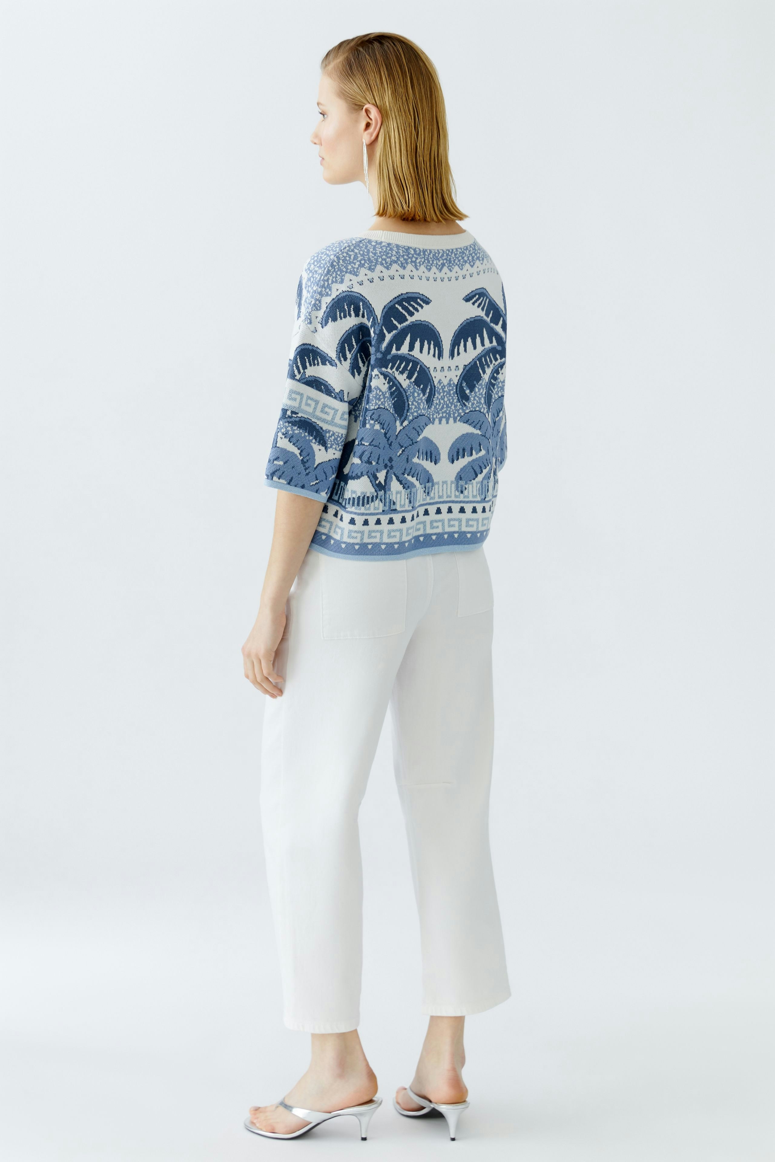 Casual women's pullover: A woman in a blue patterned pullover with three-quarter sleeves and white pants.