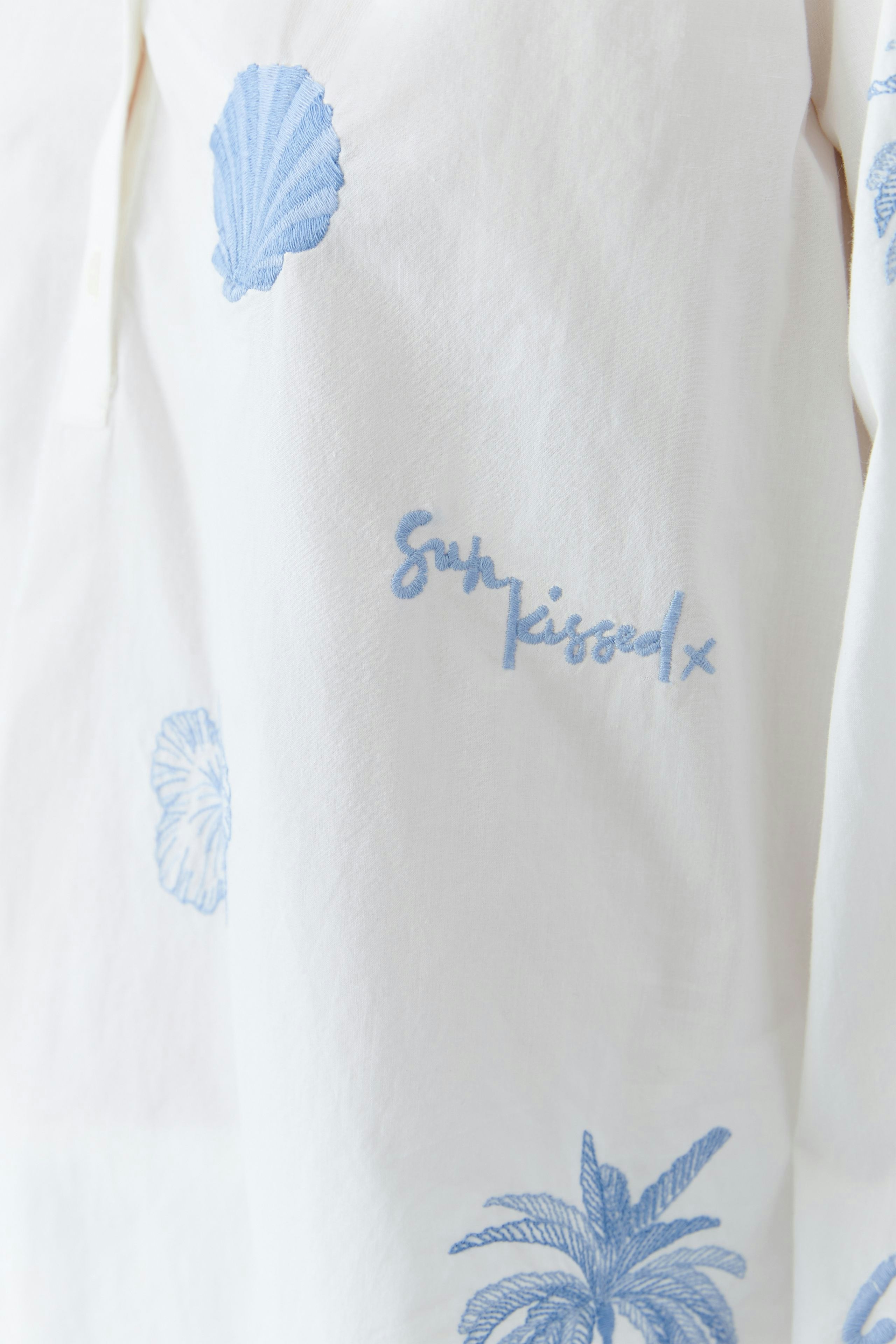 Lightweight tunic with blue shell embroidery and 'Sun kissed' text, perfect for casual summer wear.