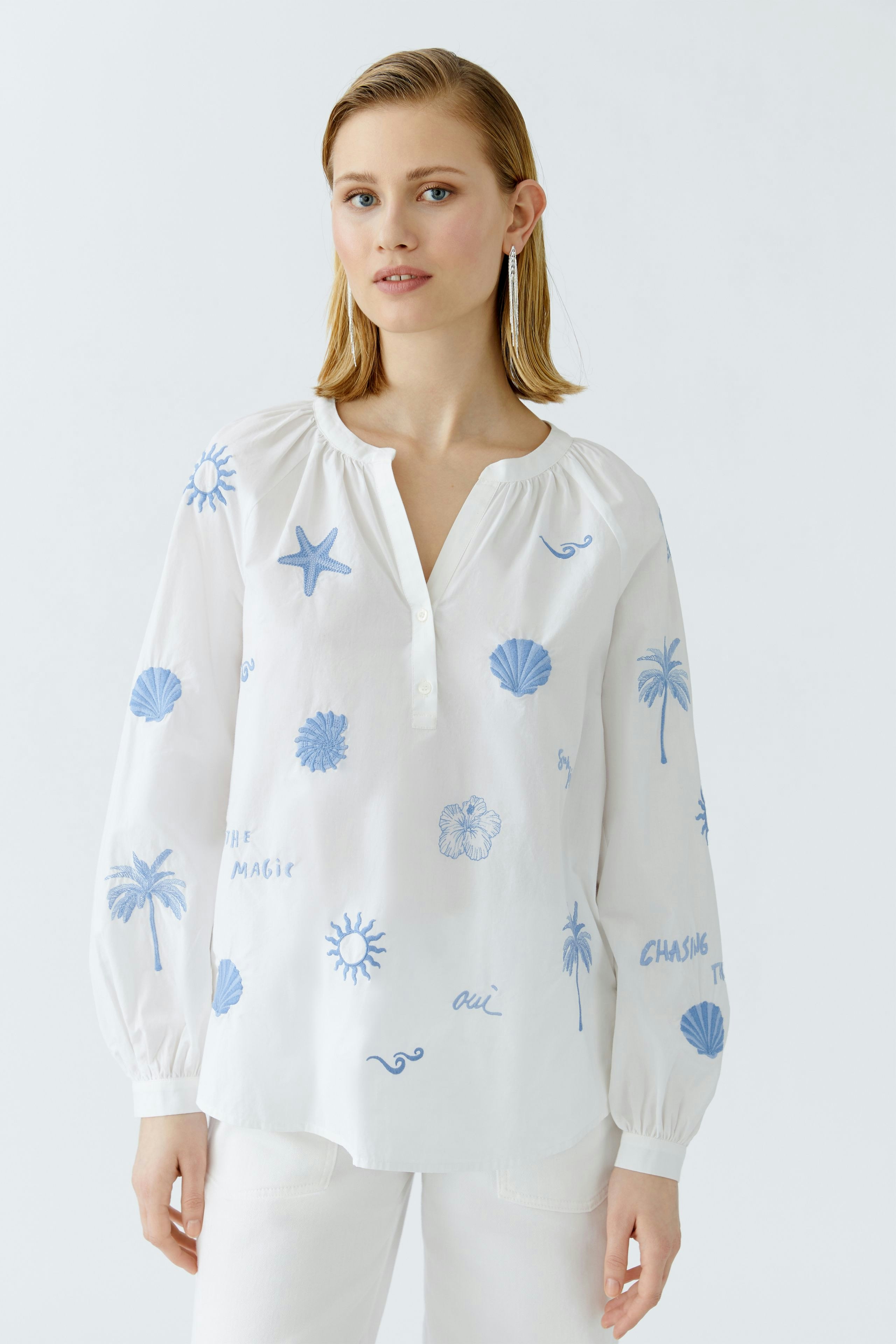 Lightweight tunic: Woman in a white tunic with blue prints, featuring a relaxed fit and button details.