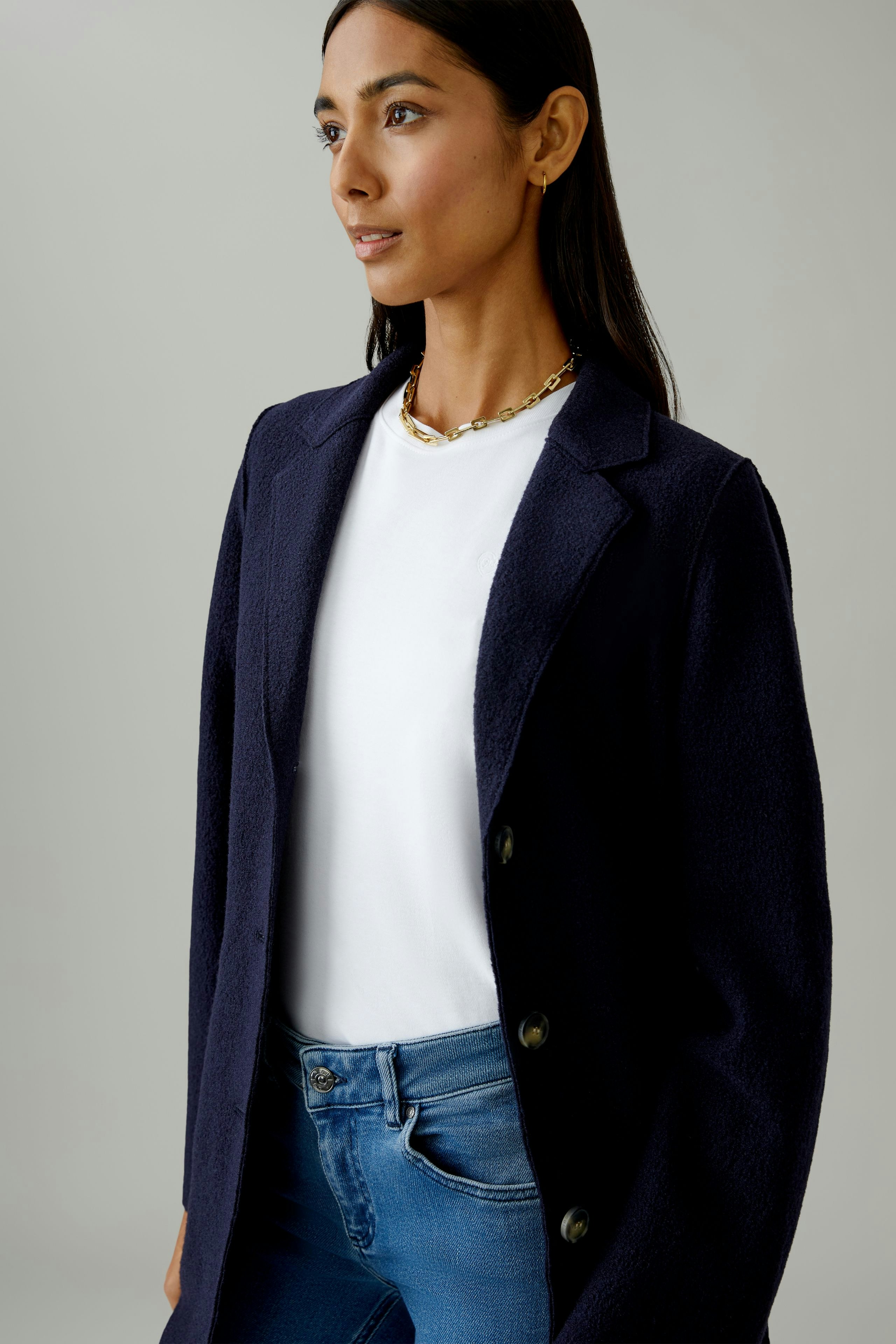Damen Wollmantel: Frau in dunkelblauem Mantel mit Knöpfen und weißem T-Shirt, lässiger Look.