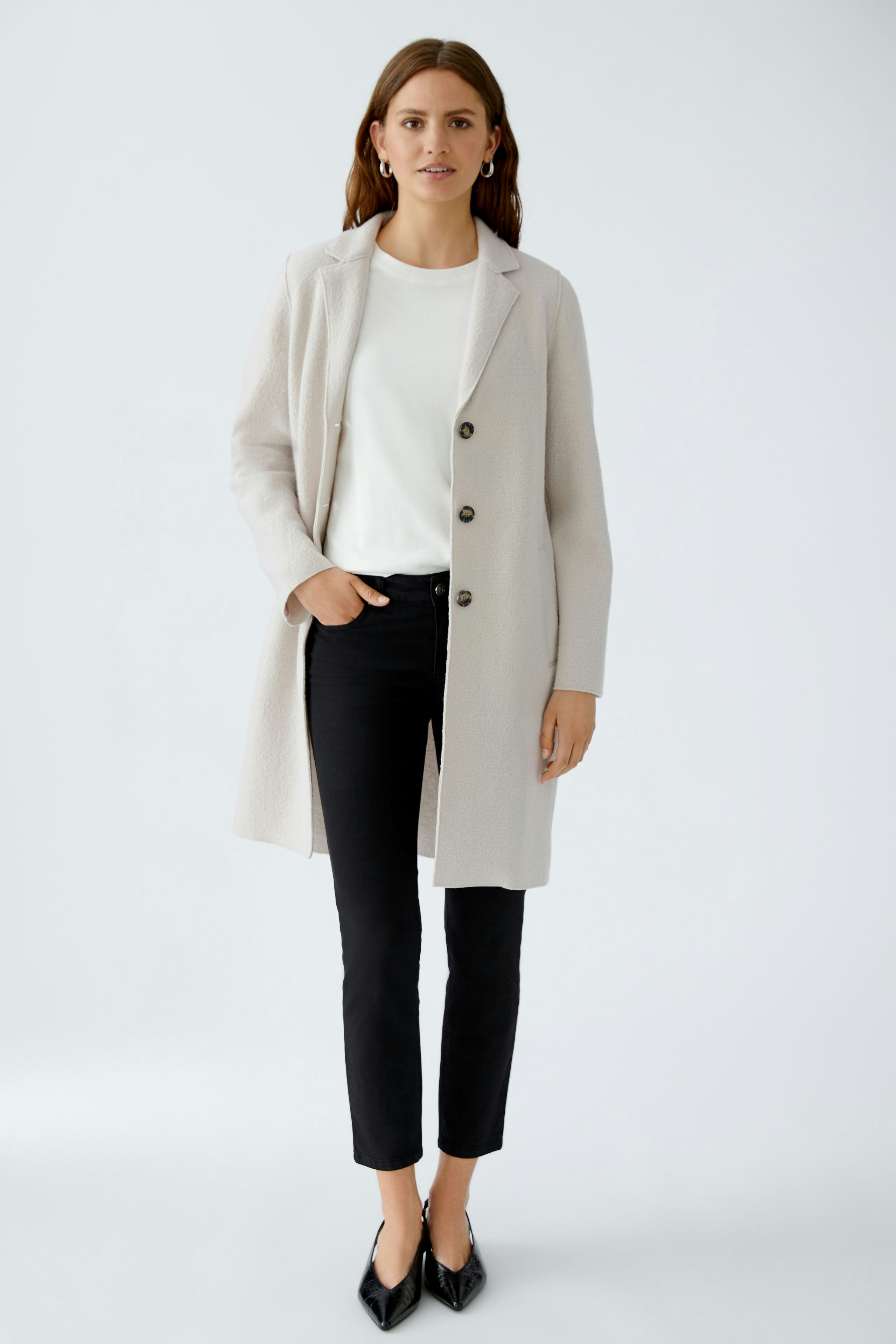 Modern women's wool coat: A woman in a light wool coat over a white top and black pants.