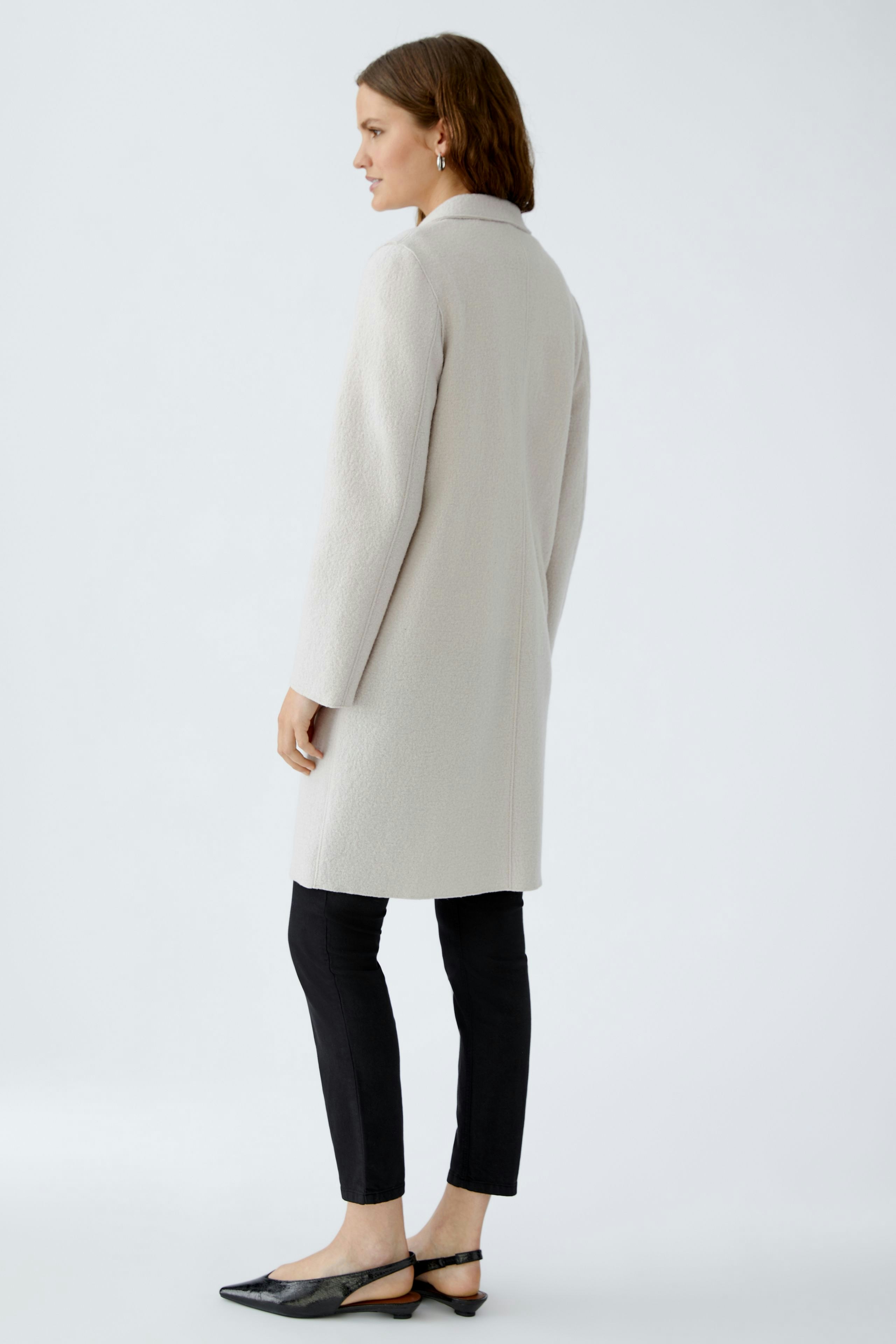 Modern women's wool coat: A woman in a light gray coat with a relaxed fit stands confidently.