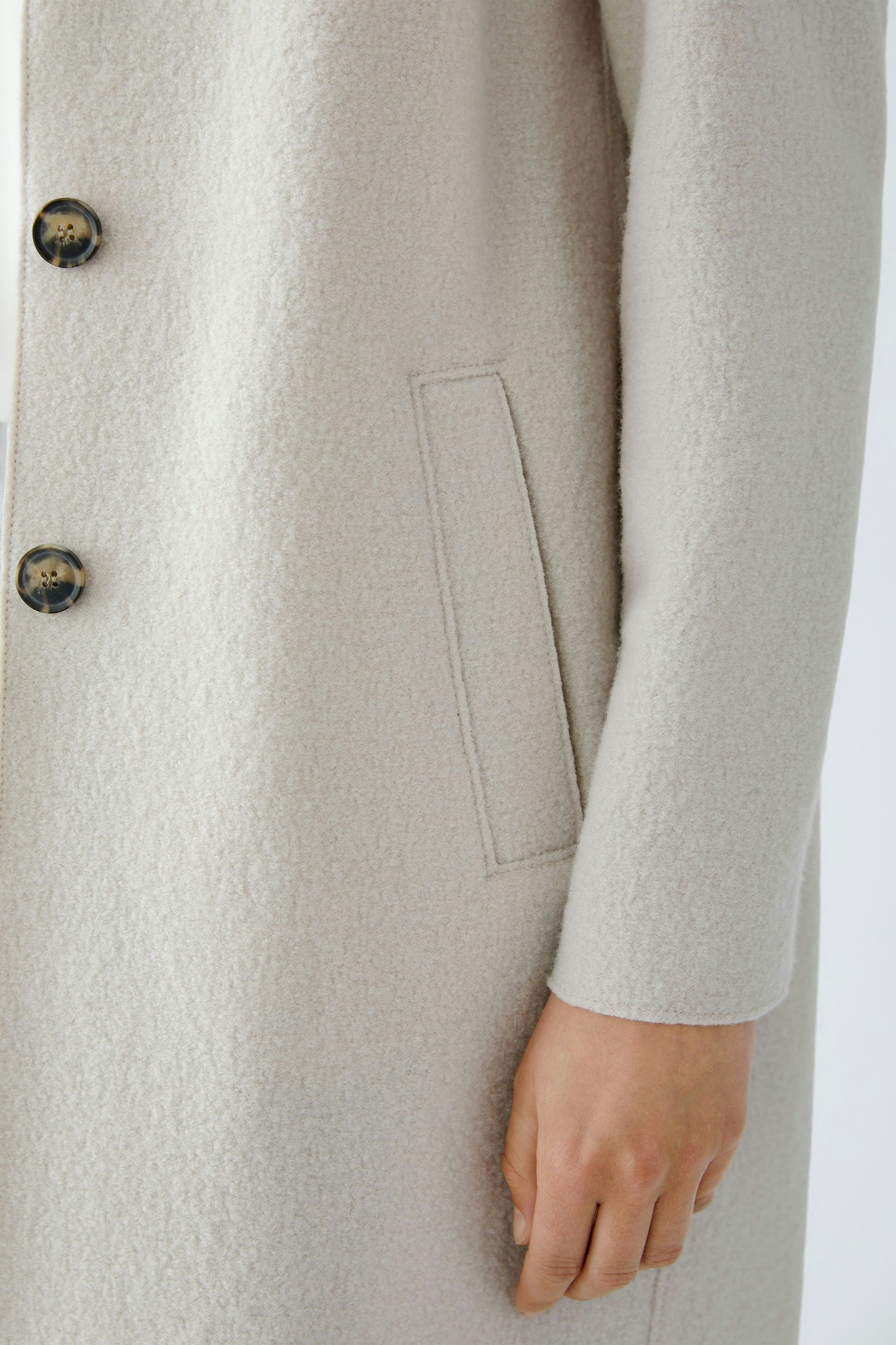 Soft wool coat: A woman showcases a light beige wool coat with buttons and side pockets.