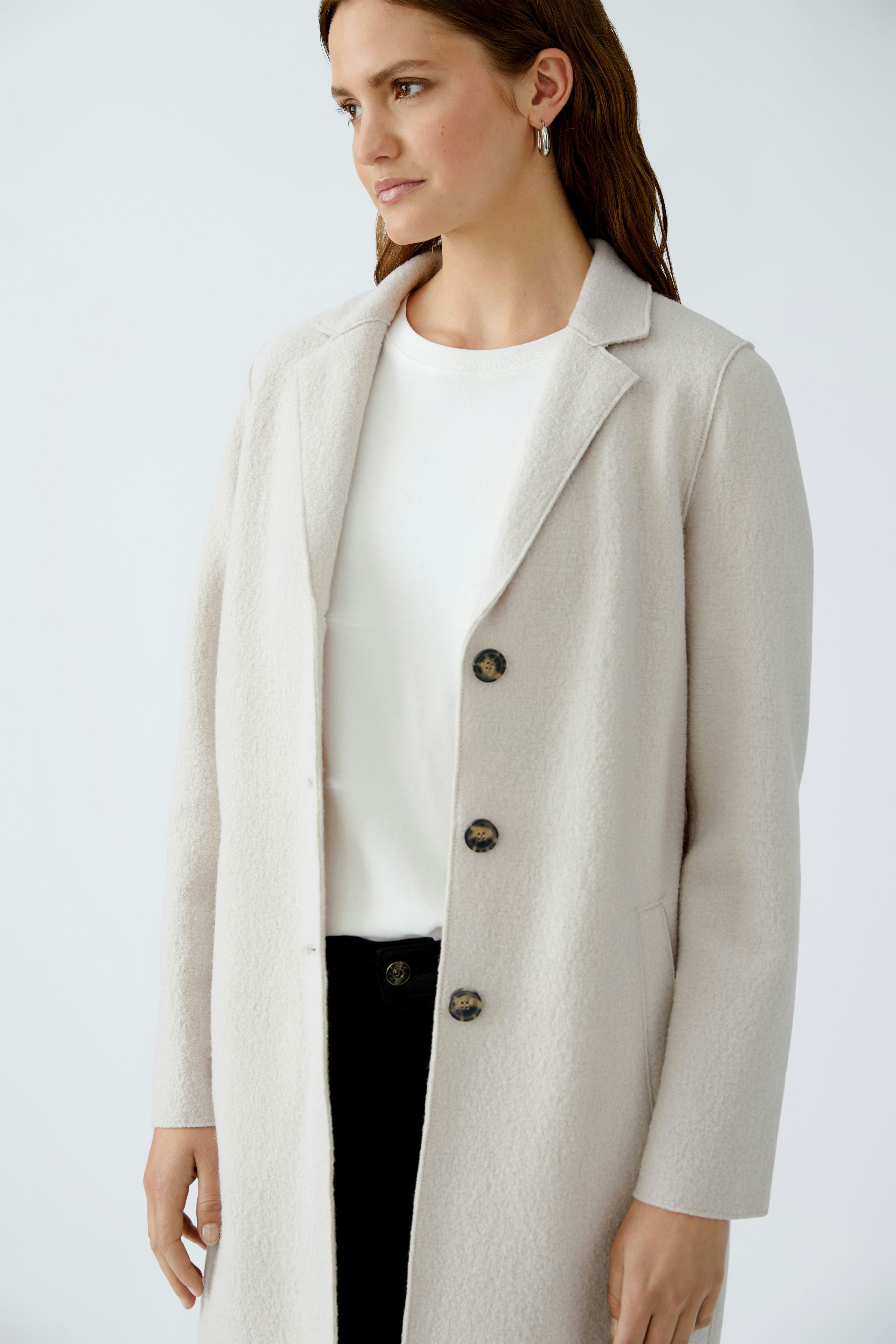 Wool coat: Woman in a light beige wool coat with a classic collar and button closure.