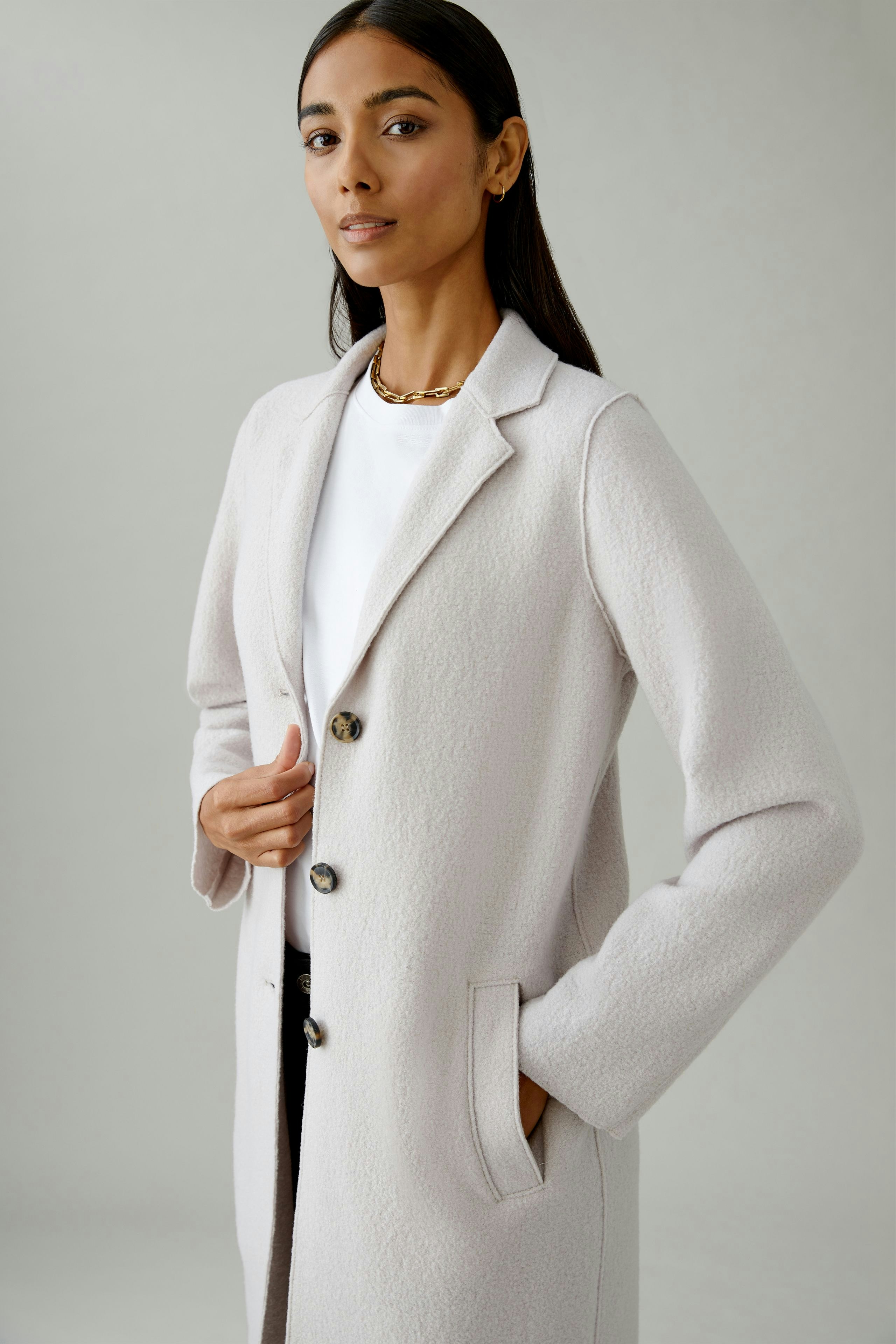 Stylish women's wool coat: A woman in a light wool coat with buttons and pockets, exuding confidence.