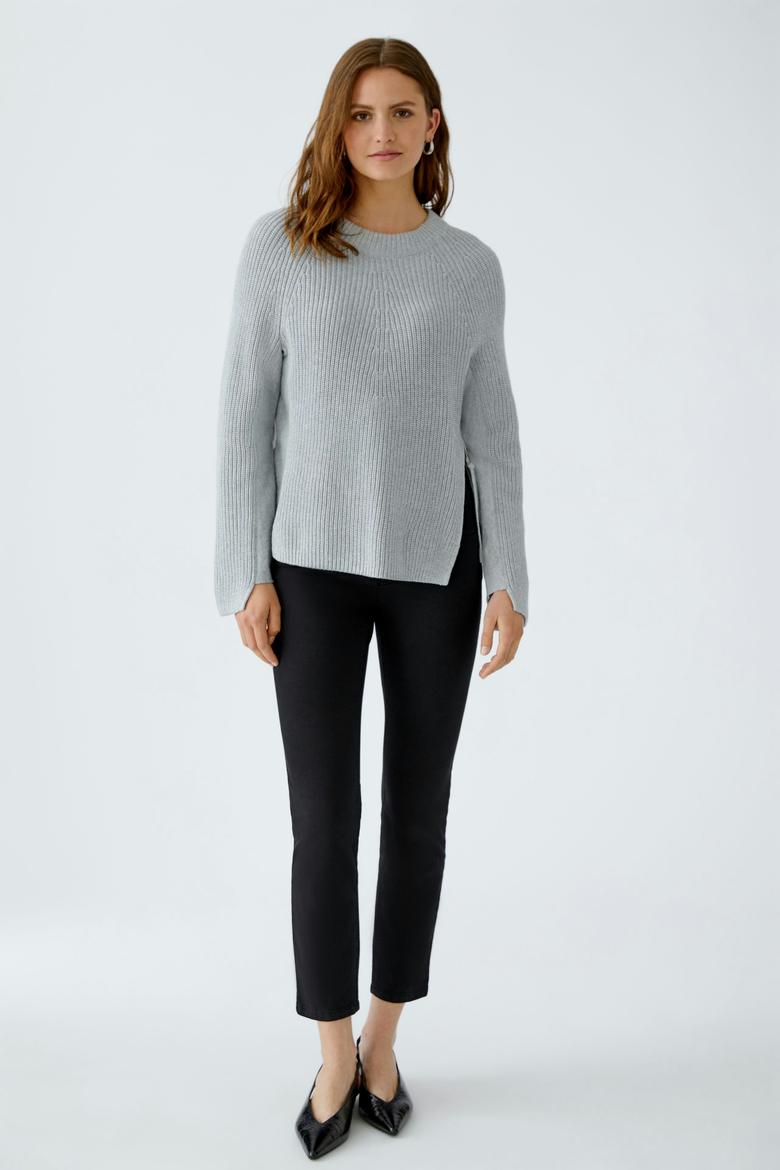 Casual women's pullover: Young woman in a light gray ribbed pullover paired with black pants.
