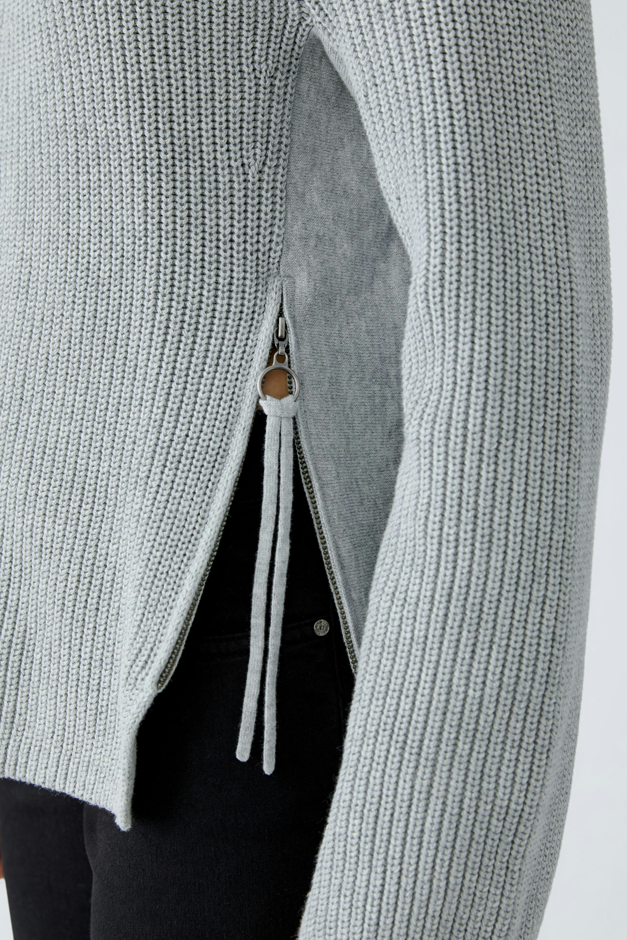 Casual women's pullover: A woman in a light gray knitted pullover with side zippers, styled effortlessly.