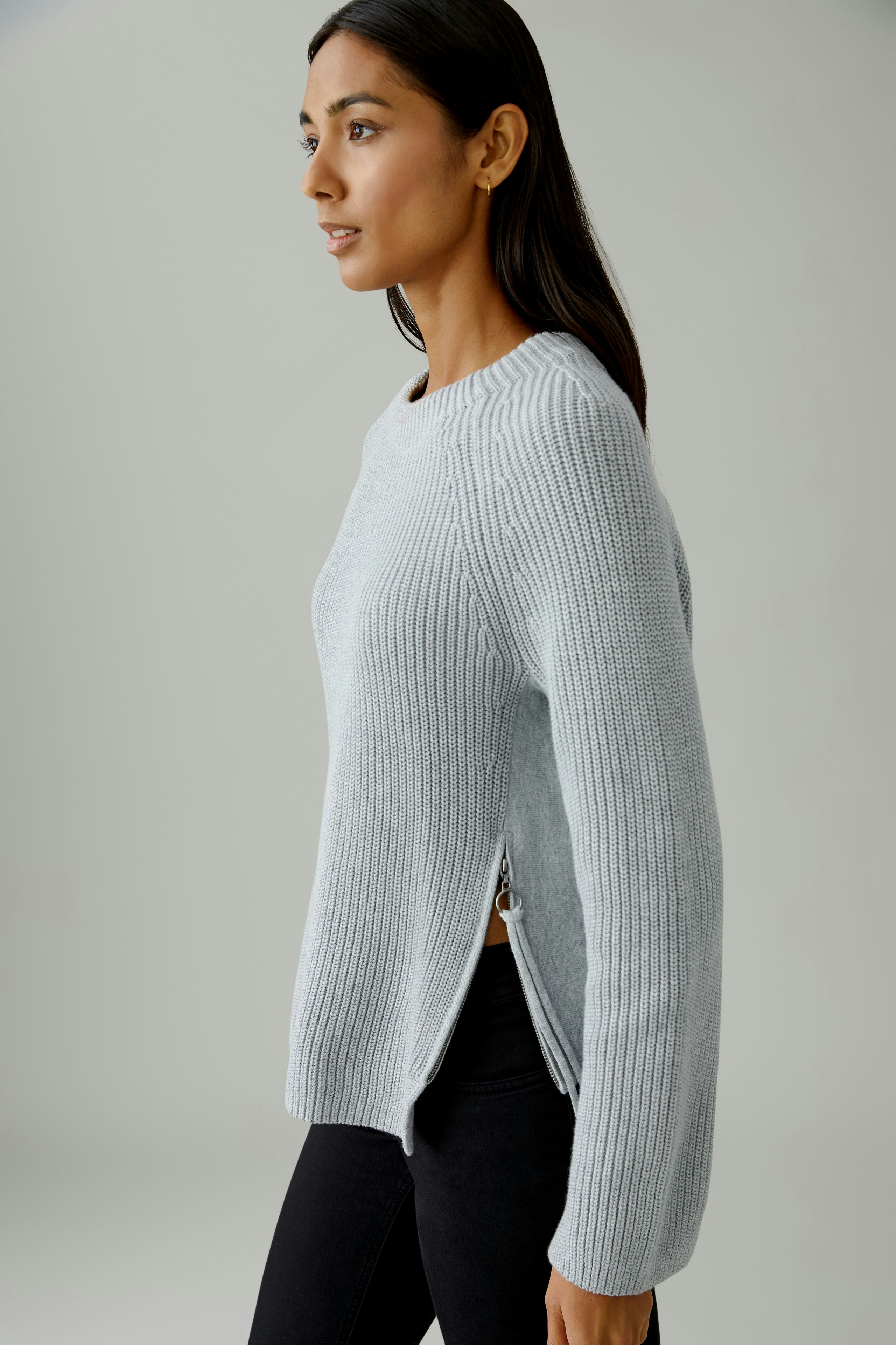 Casual women's pullover: A woman in a light blue ribbed pullover with side slits, paired with black pants.