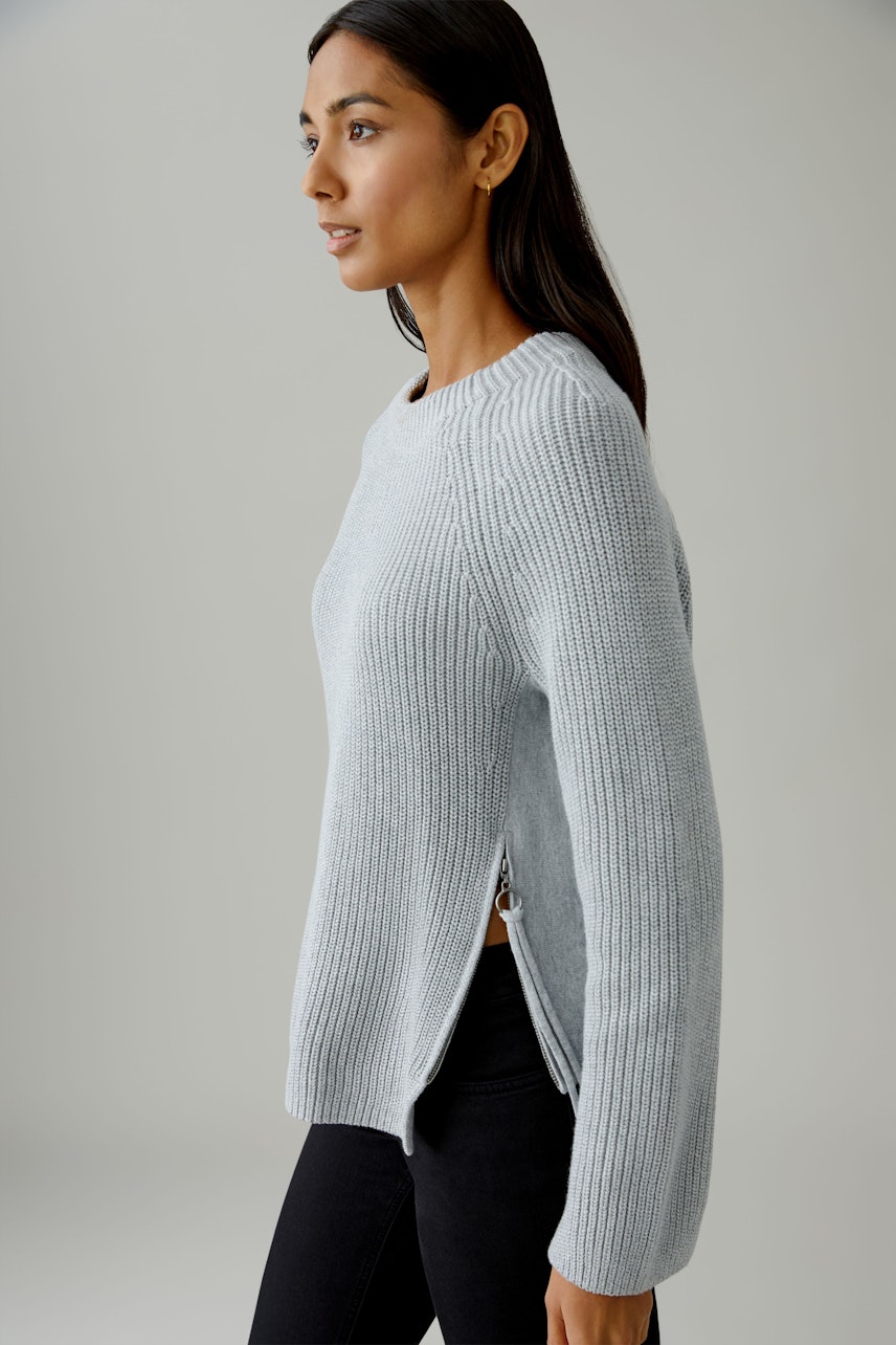Damen-Pullover: Frau in hellblauem Strickpullover mit seitlichen Schlitzen und lässigem Schnitt.