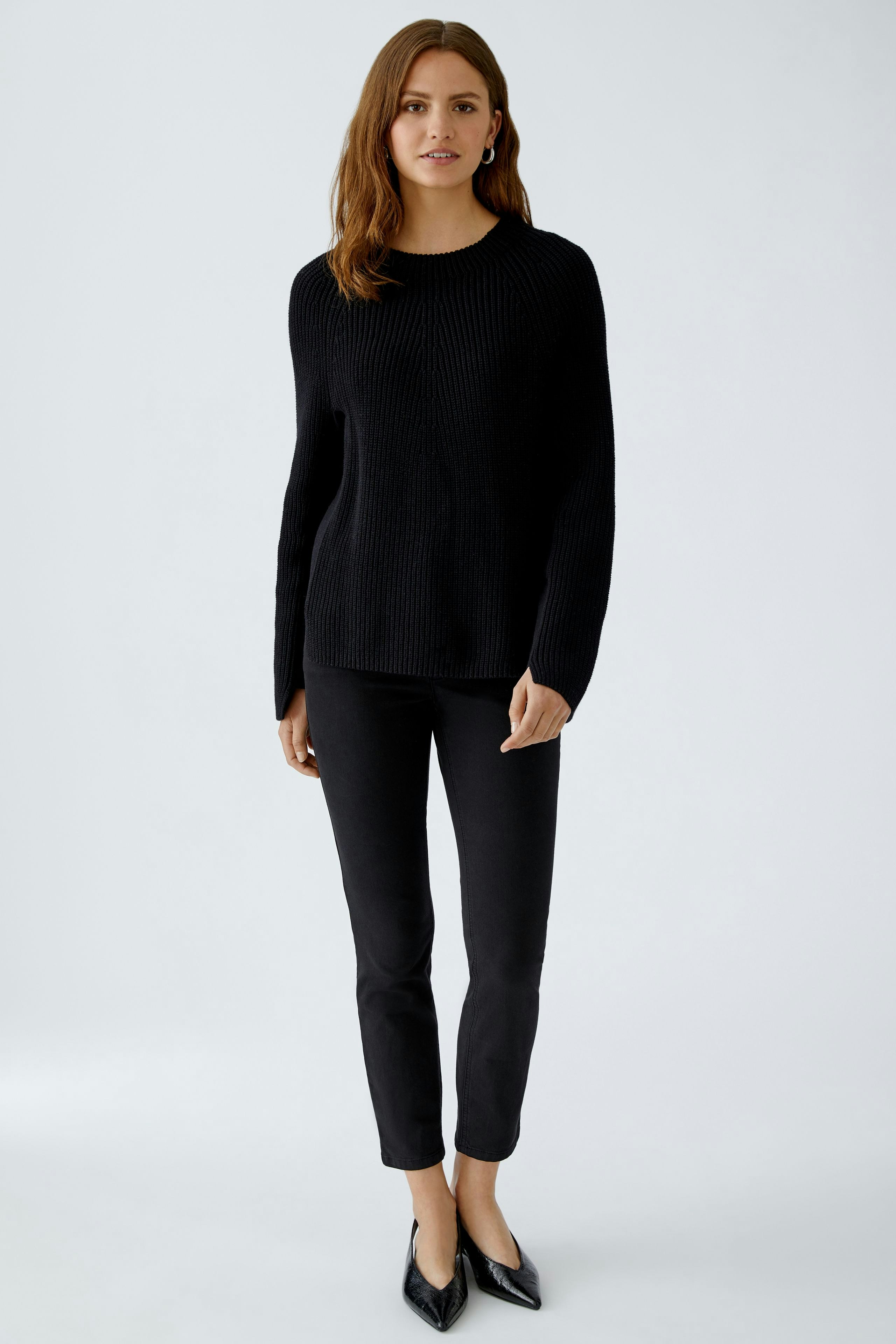 Casual women's pullover: Young woman in a black ribbed pullover paired with black pants.