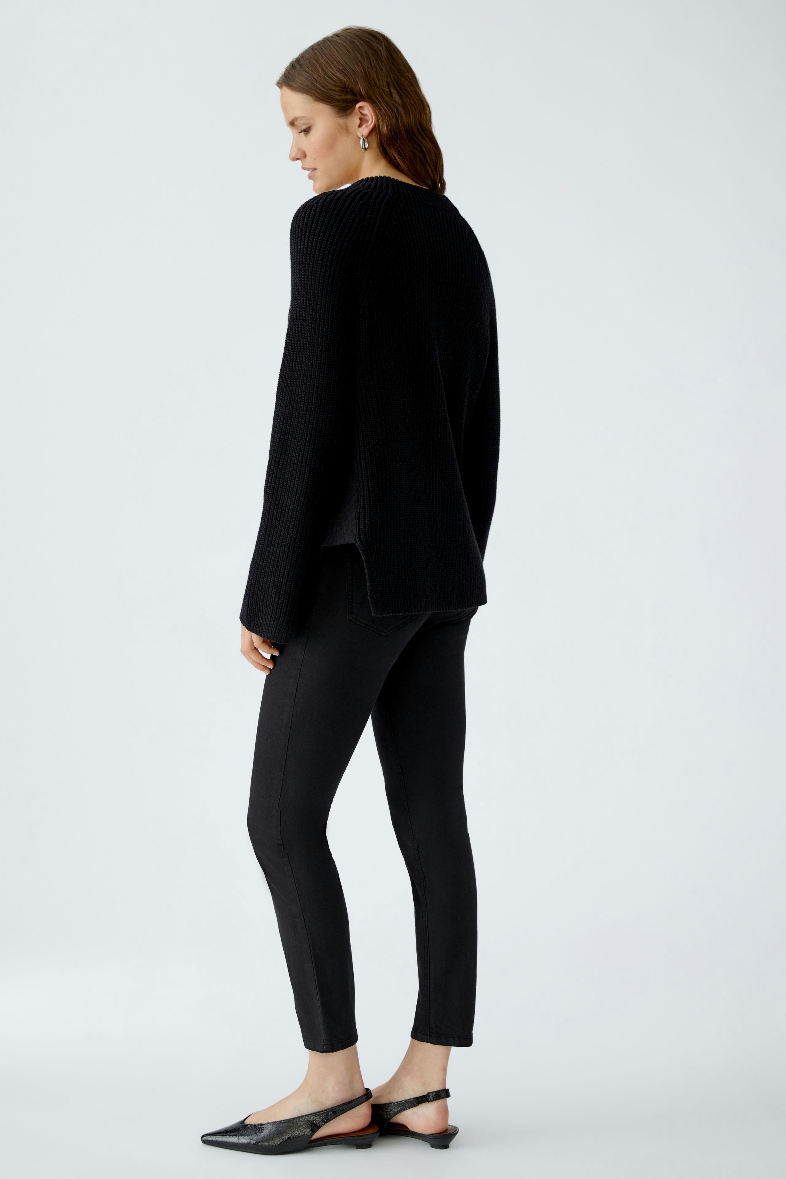 Casual women's pullover: A woman in a black knitted pullover with a relaxed fit, paired with black pants.