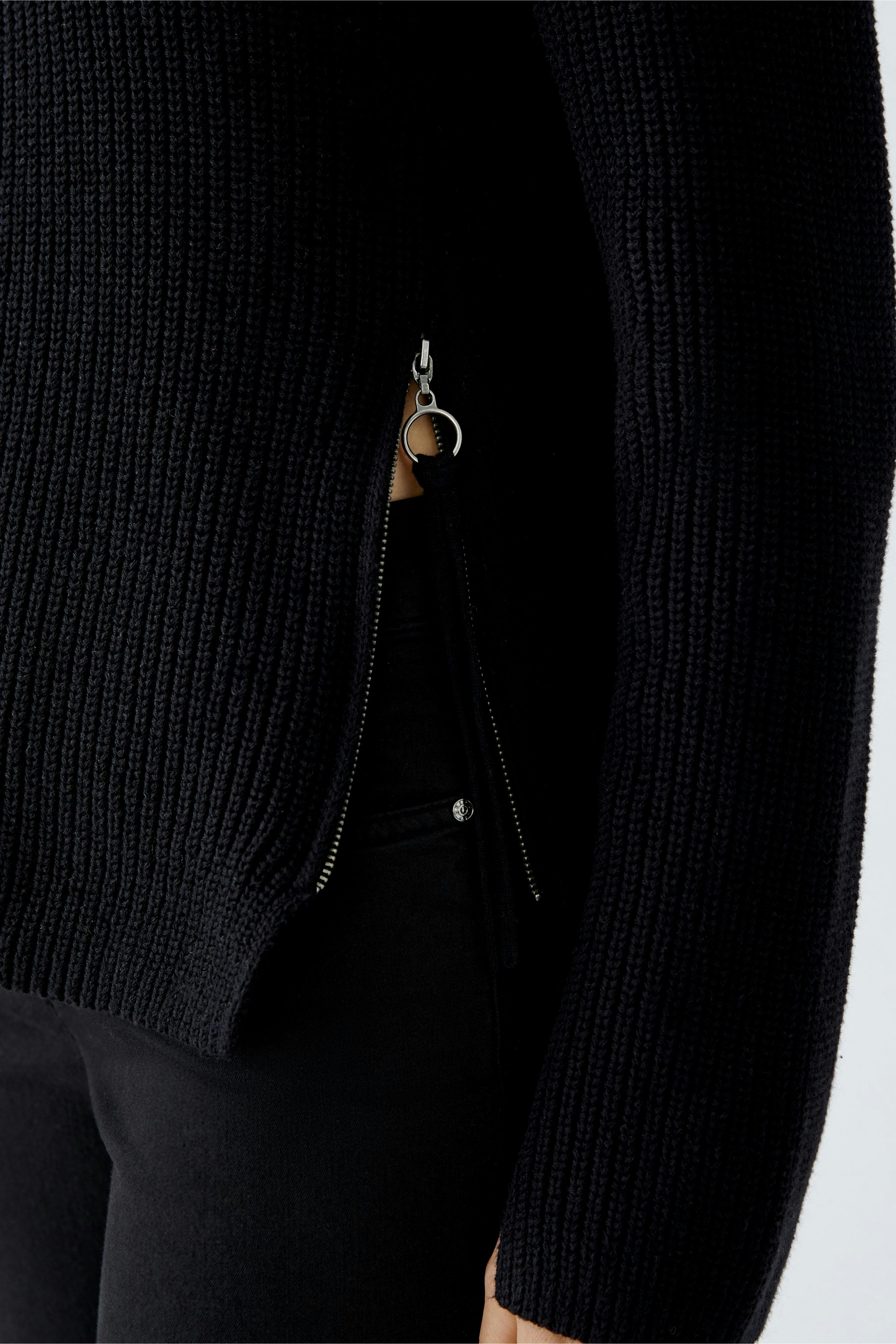 Casual women's pullover: Close-up of a woman in a black ribbed pullover with a stylish zipper detail.