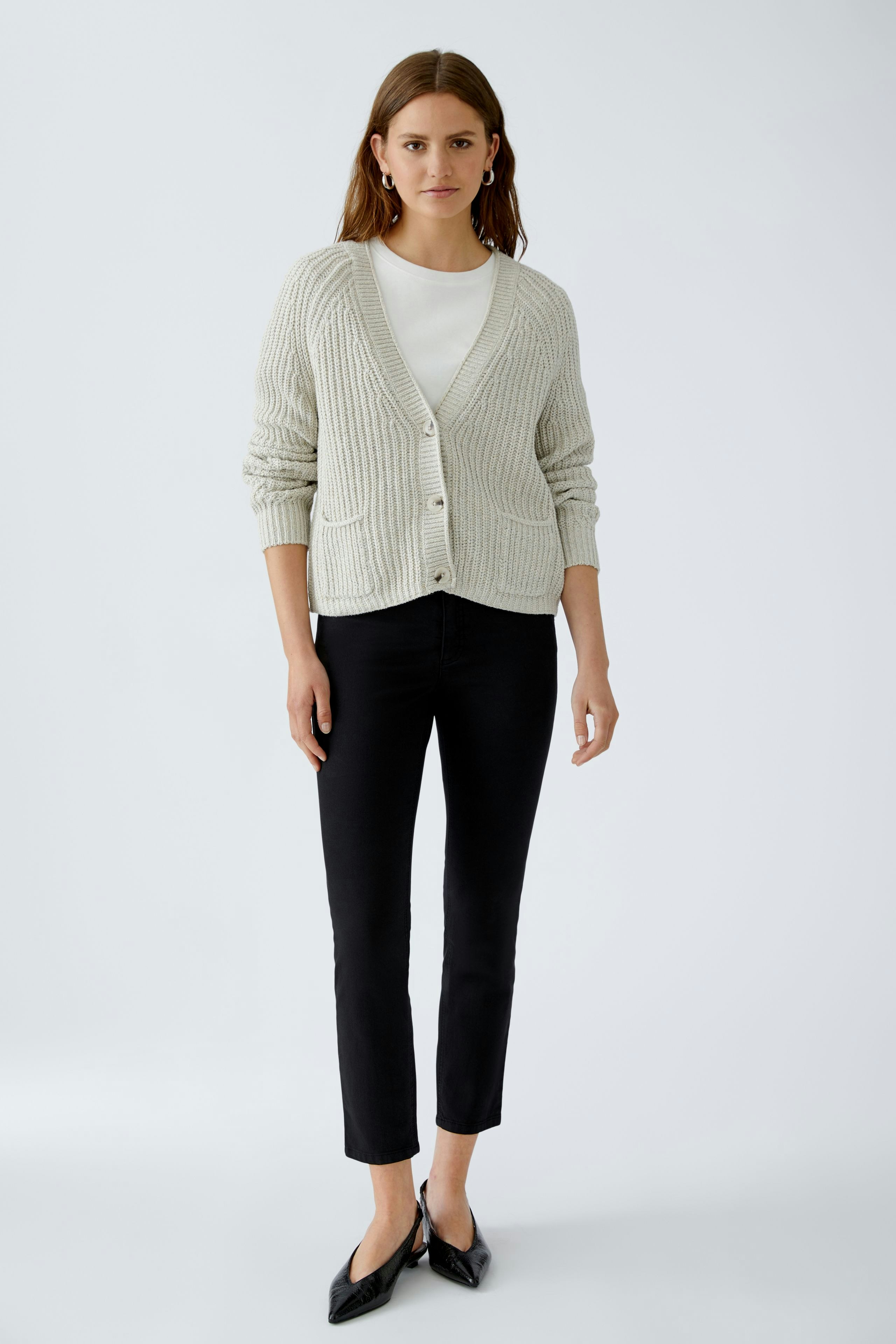 Bequeme Damen-Strickjacke: Frau in hellgrauer Strickjacke mit Knöpfen und Taschen, kombiniert mit schwarzer Hose.