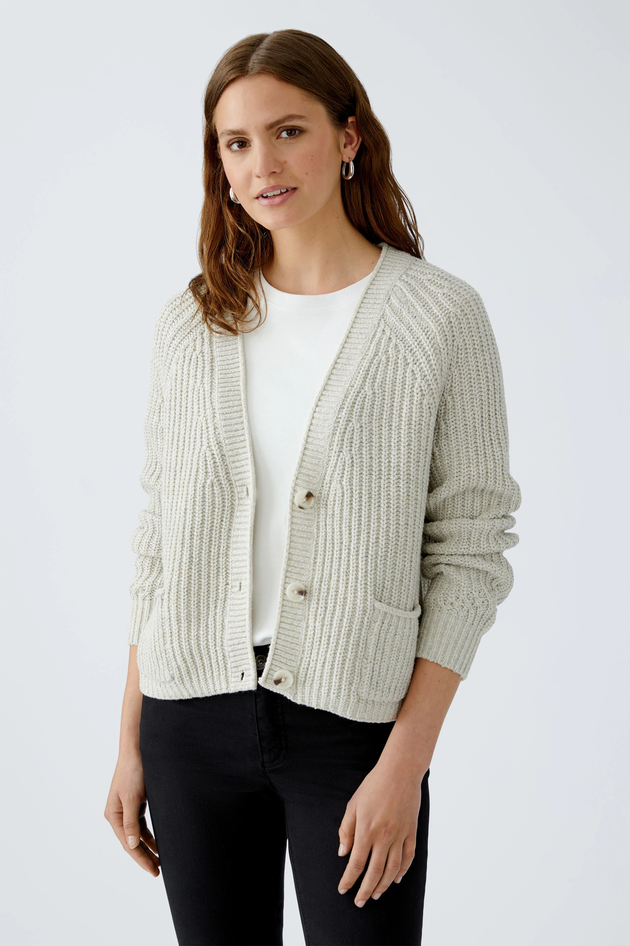 Casual women's cardigan: Young woman in a light knitted cardigan with buttons and pockets, smiling.