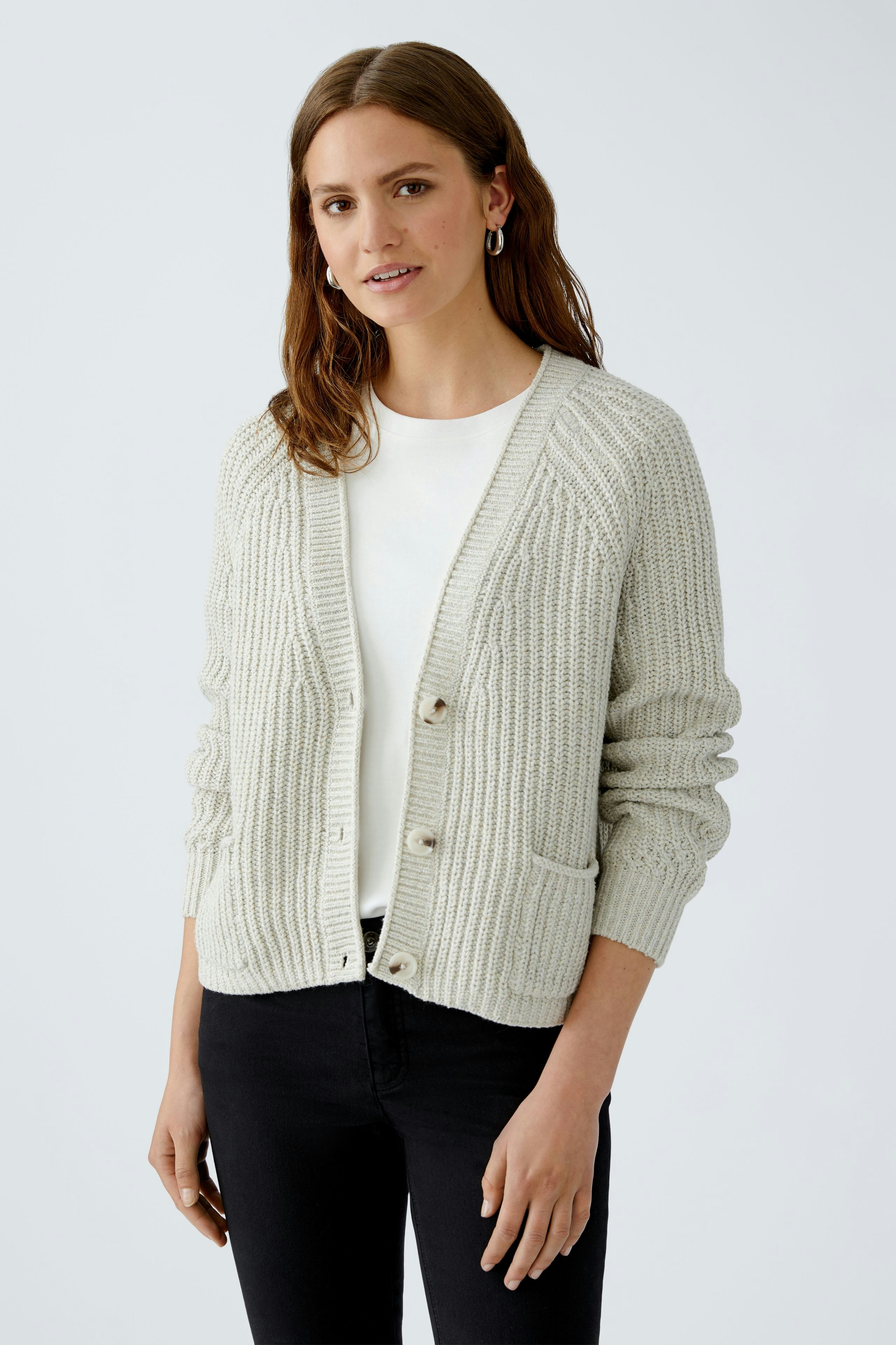 Bequeme Damen-Strickjacke: Frau in heller Strickjacke mit Knöpfen und Taschen, lässig kombiniert.