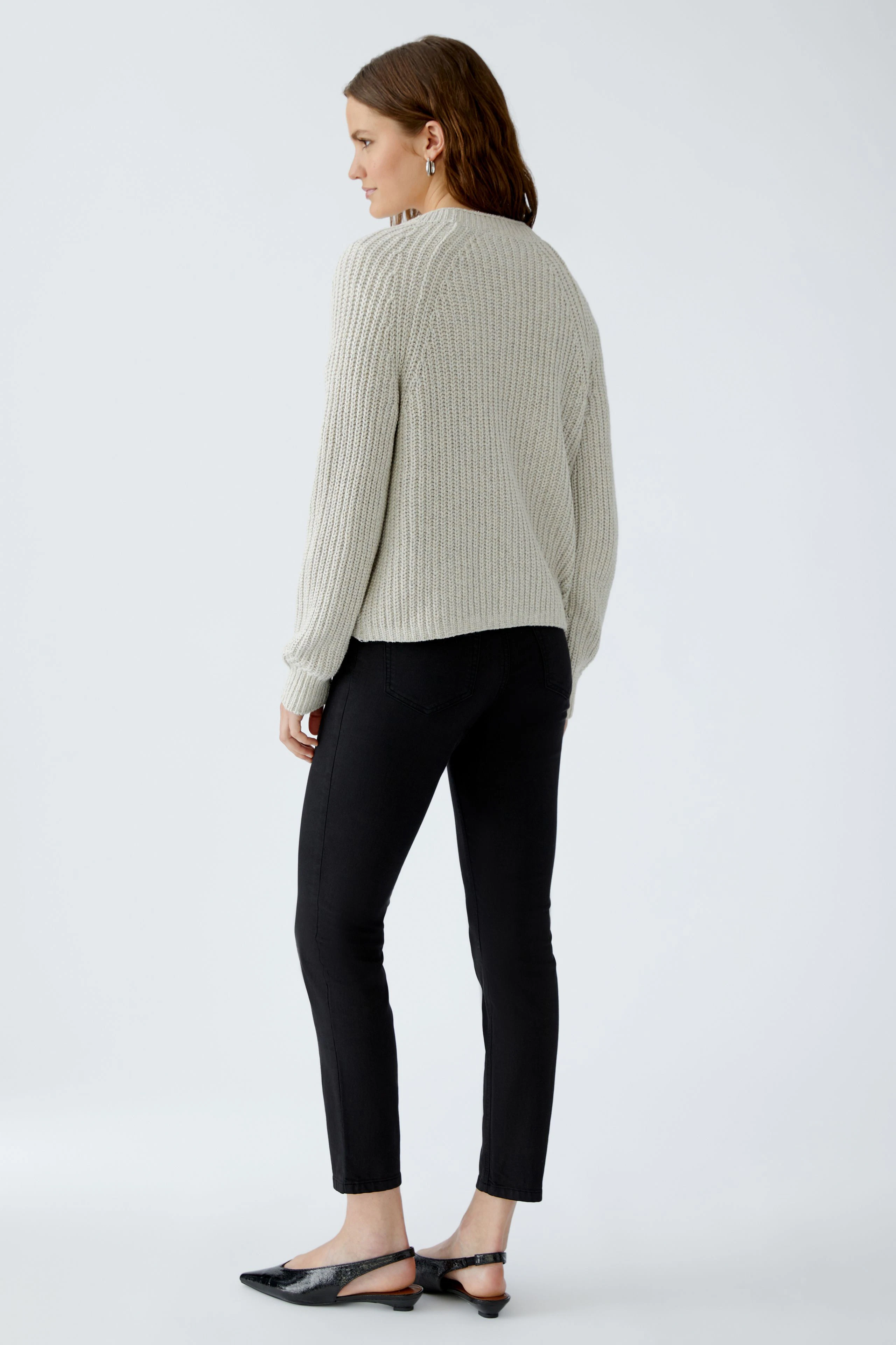 Casual women's cardigan: A woman in a light gray ribbed cardigan, paired with black pants, stands confidently.